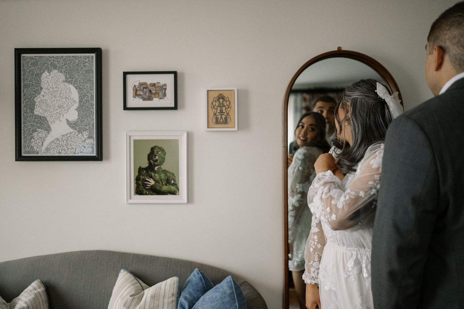 A couple gets ready in a cozy room with framed artwork on the walls.