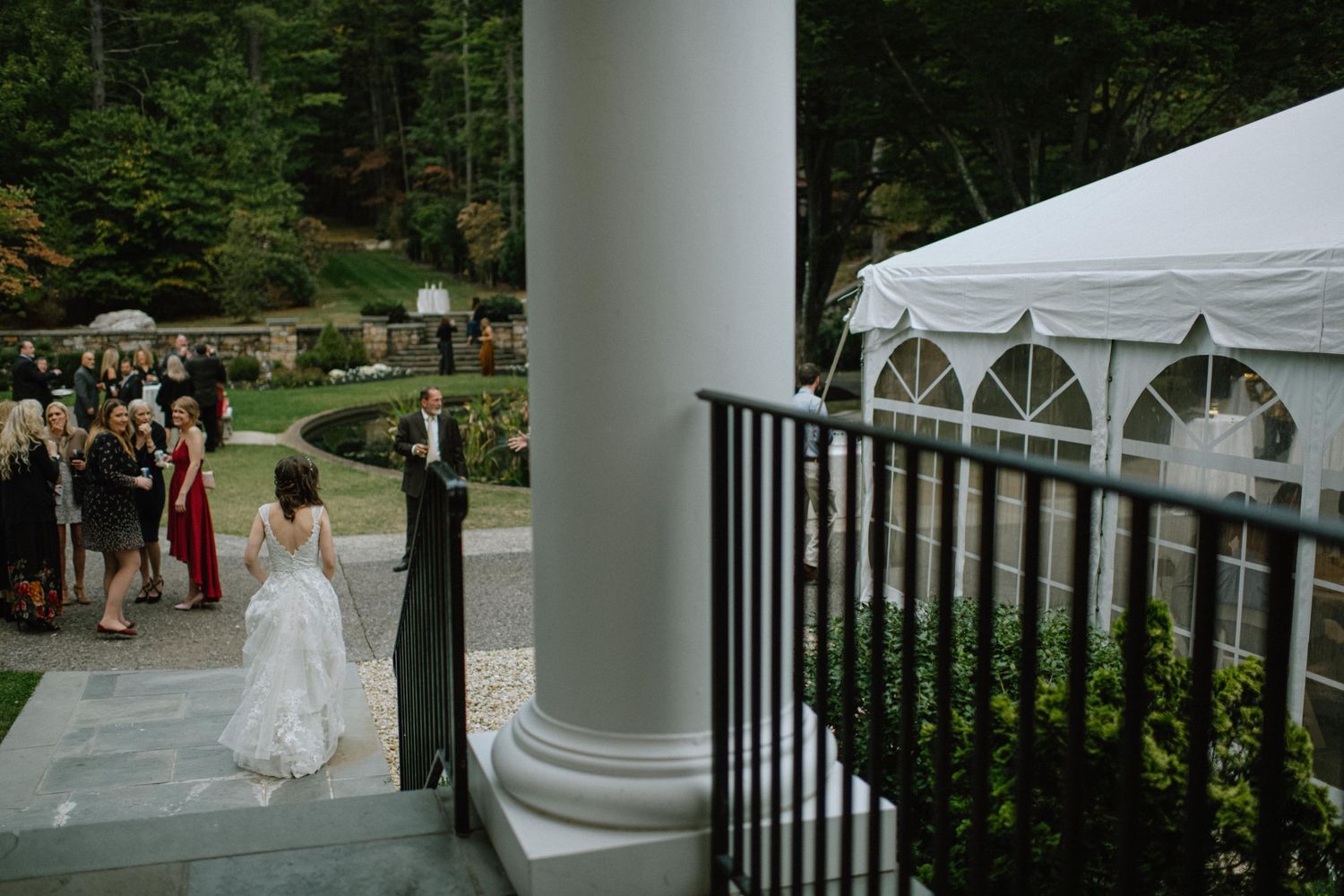 Outdoor wedding venue with white columns and tent set up on stone patio.