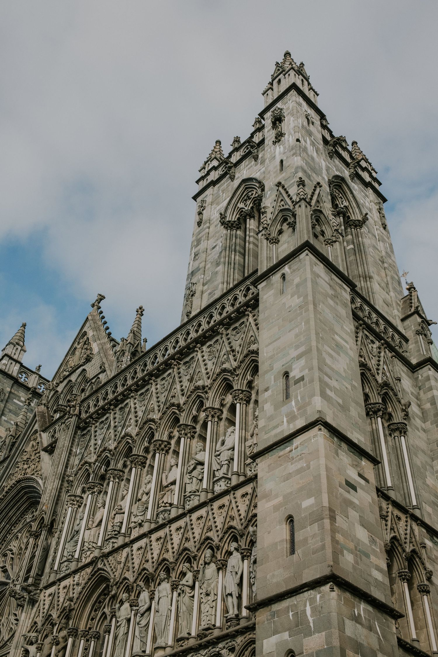 Detailed gothic architecture of a cathedral tower featuring ornate stone carvings and pointed arches.
