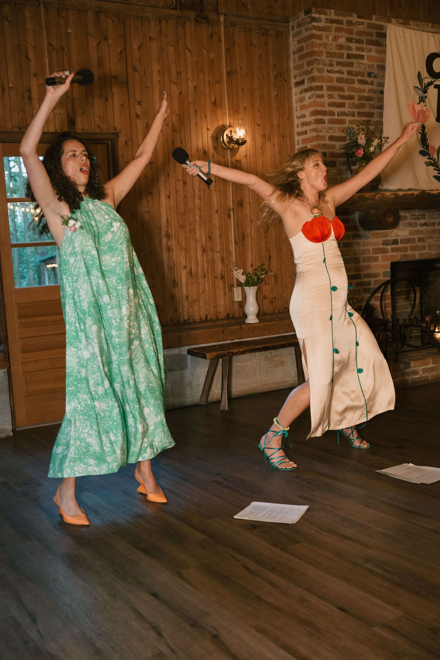 Two guests dancing joyfully on wooden floor at reception celebration.