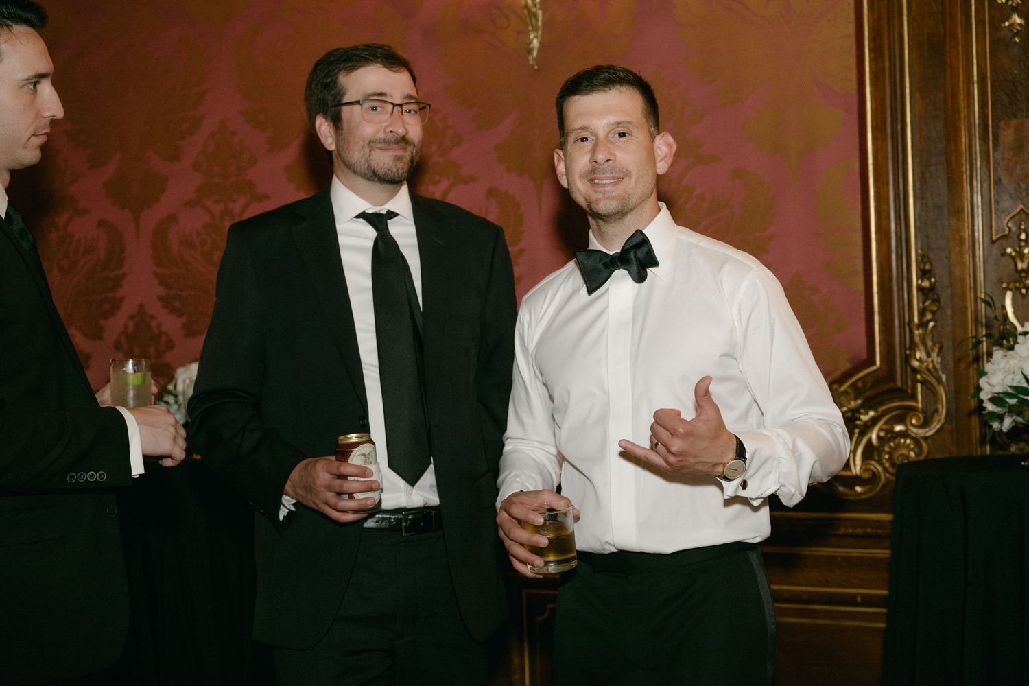 Guests mingling and socializing at an upscale wedding reception with red wallpaper.