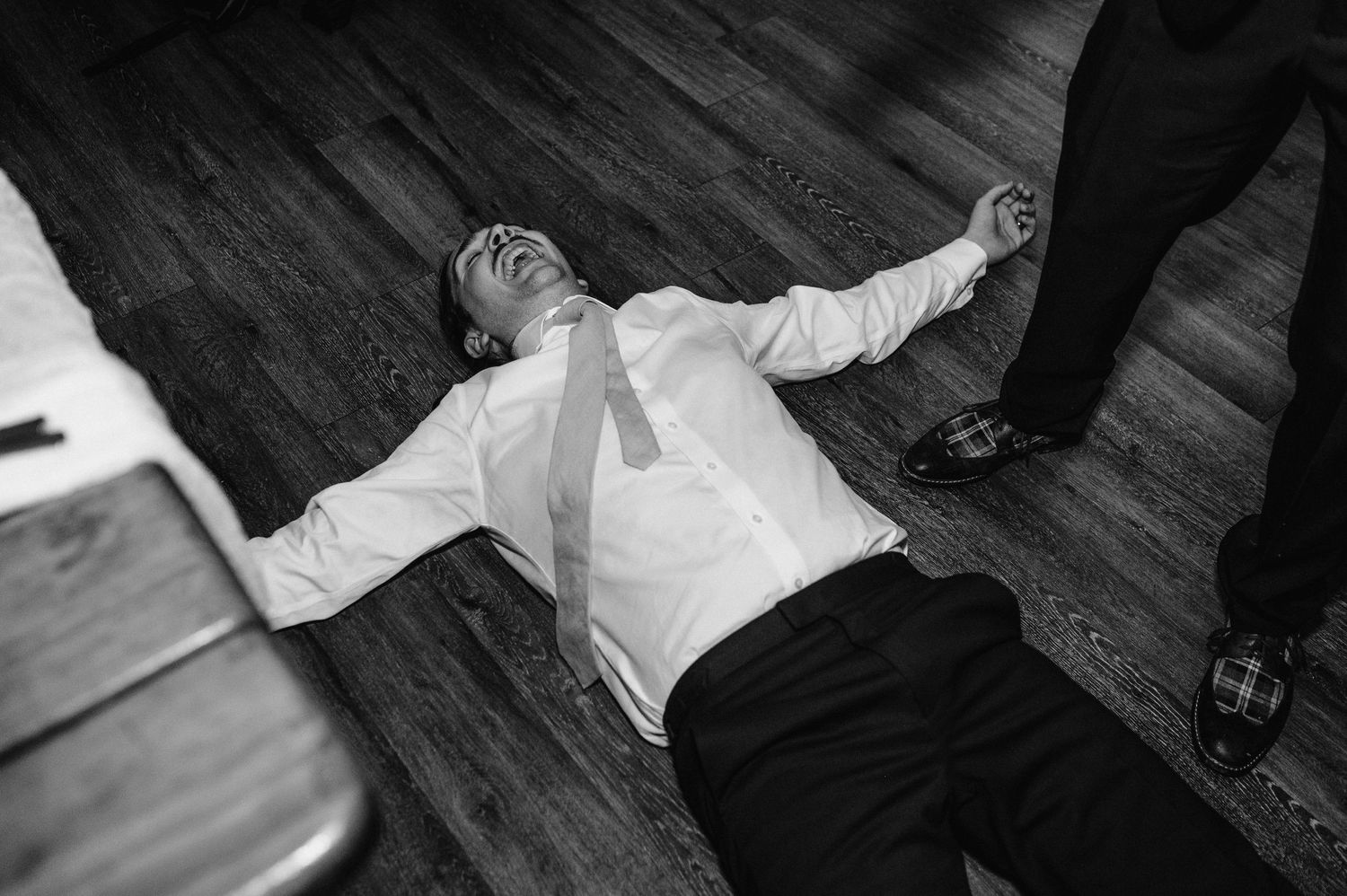 Person in white shirt lying on wooden floor at wedding reception celebration.