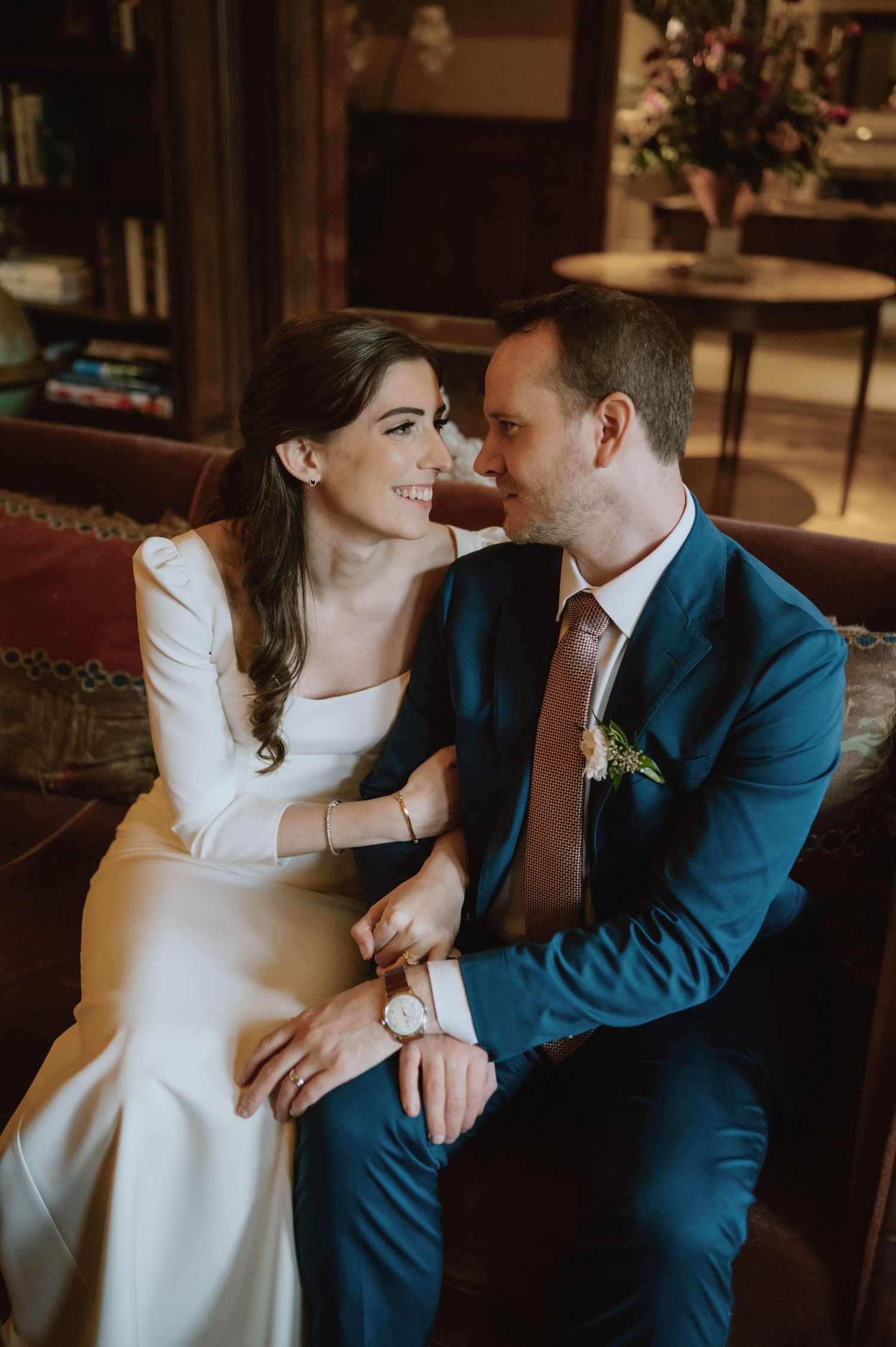 A romantic moment captured between a couple in wedding attire sitting on an elegant couch.
