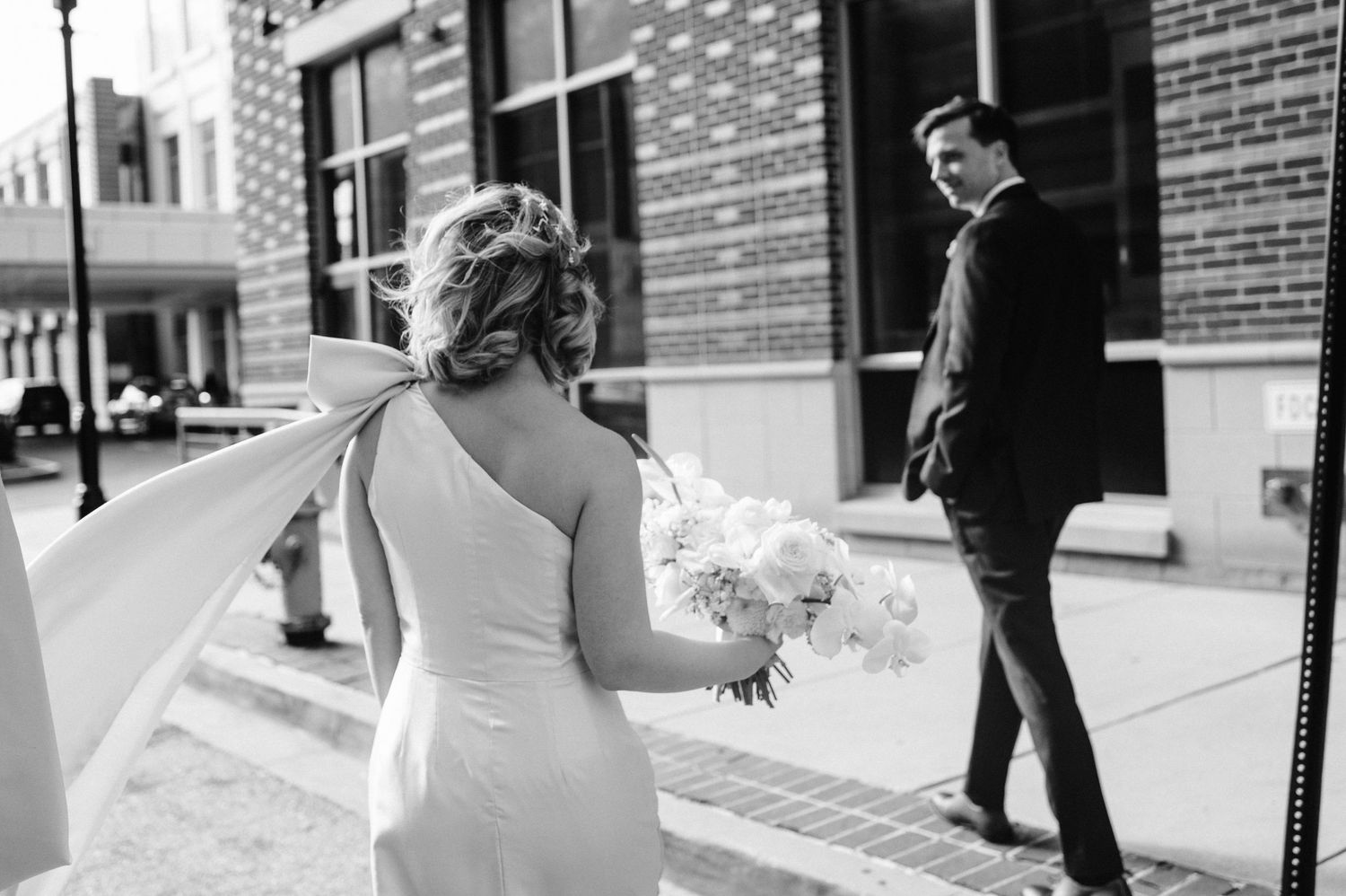 Black and white photo of a wedding moment on a city street.