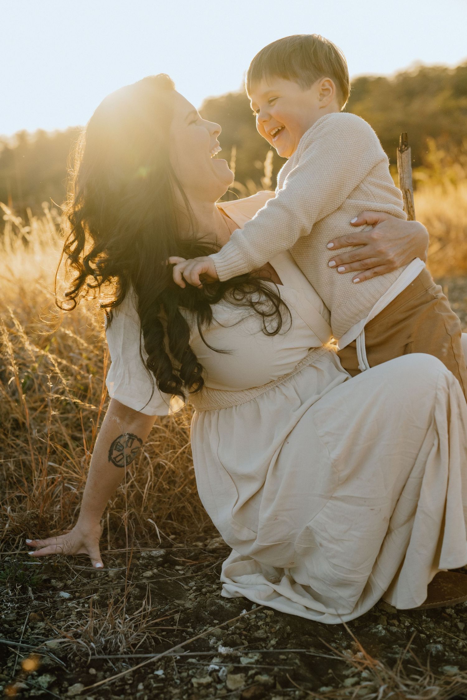 A joyful moment between parent and child laughing together in a sunlit meadow.