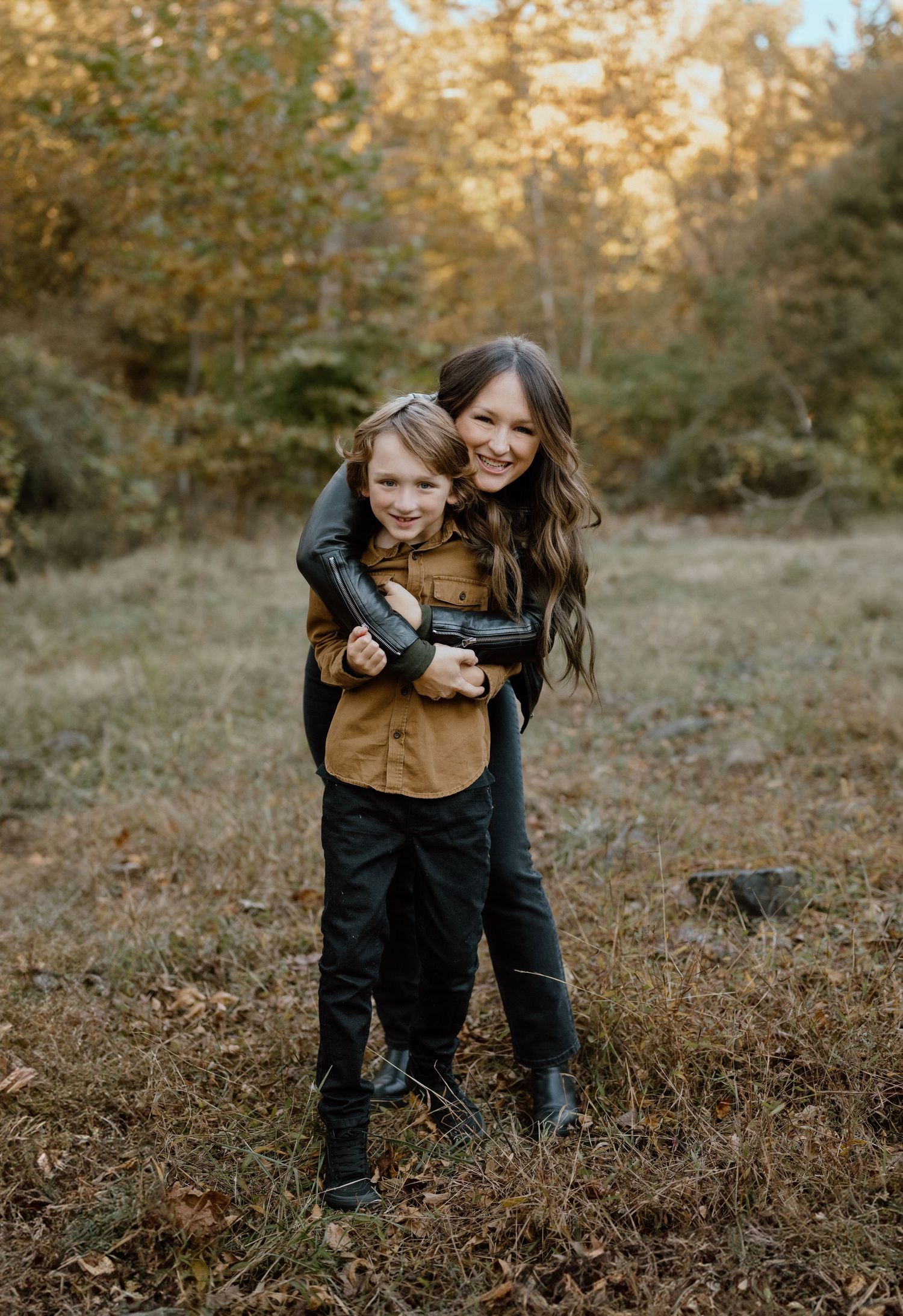 Playful autumn portrait session in a wooded setting with warm golden light.