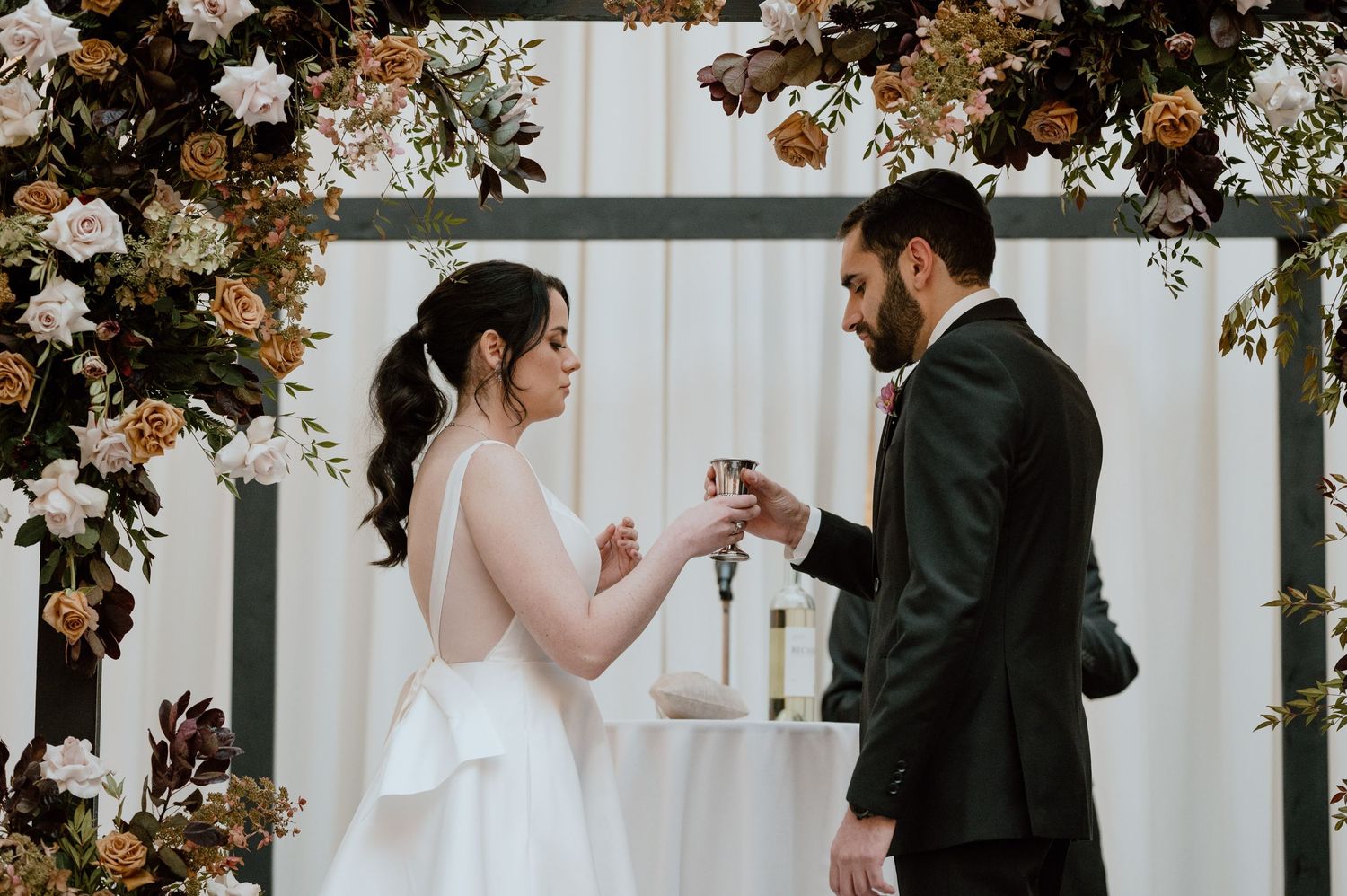 Wedding ceremony moment under a floral arch with romantic lighting.
