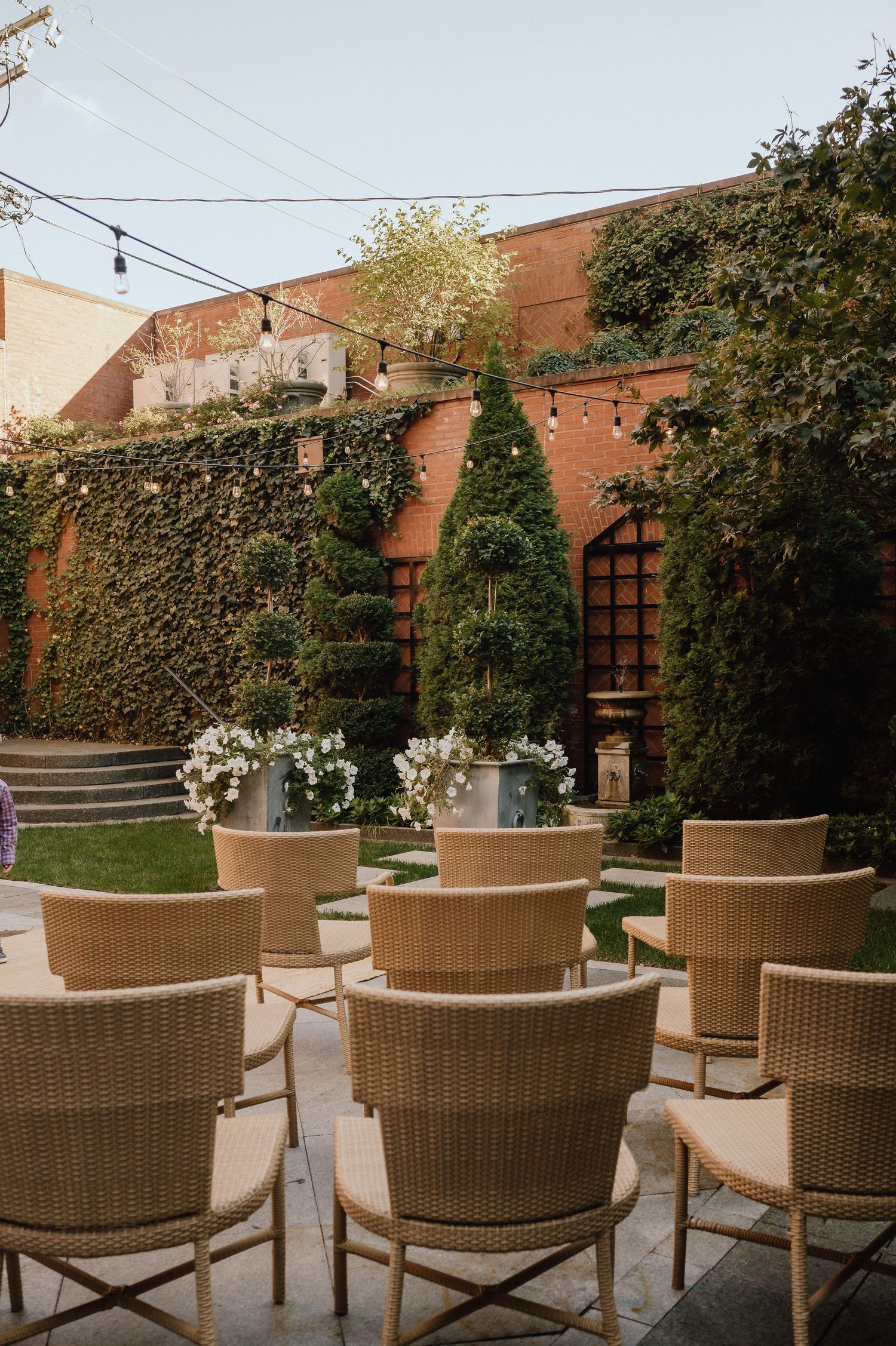 An elegant outdoor venue with ivy-covered walls and wicker chairs arranged for an event.