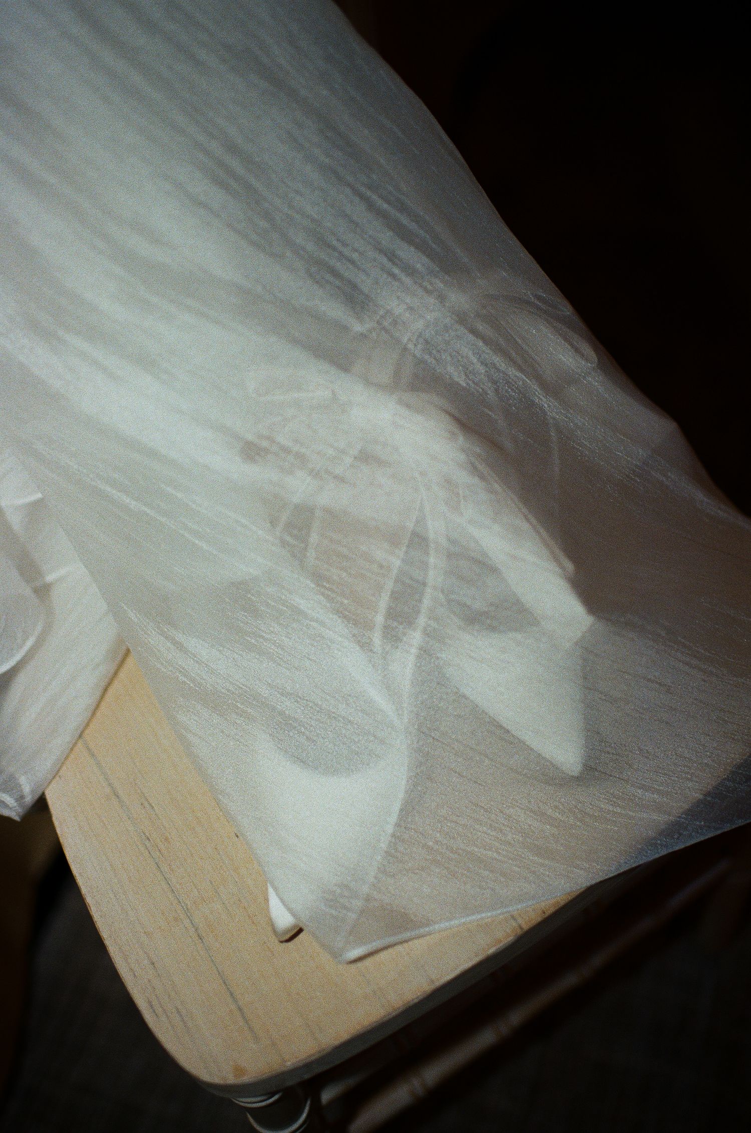 White tulle fabric drapes across a wooden floor in soft lighting.