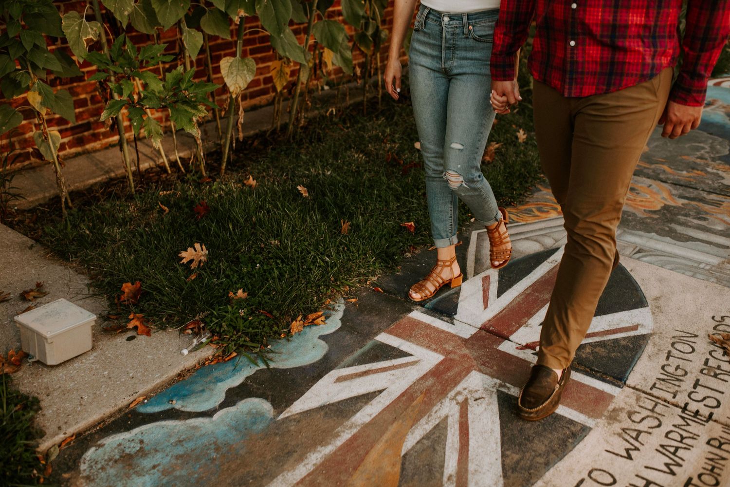 Legs of couple walking on decorated sidewalk with painted design.
