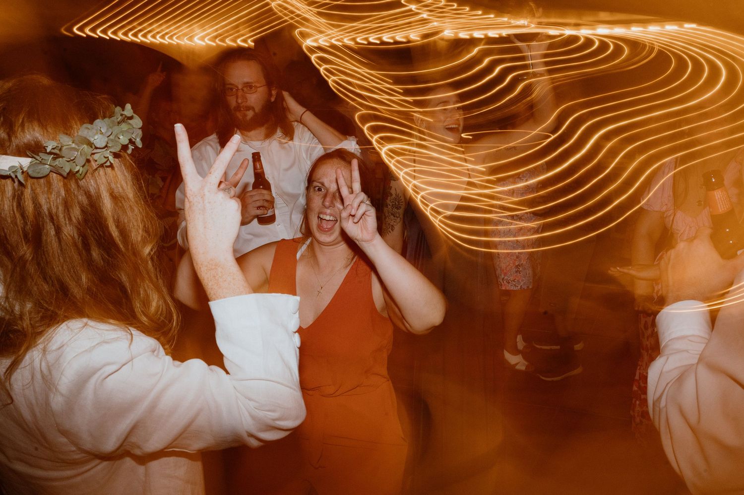 Vibrant orange-tinted party scene with dancing and light trails creating an energetic atmosphere.