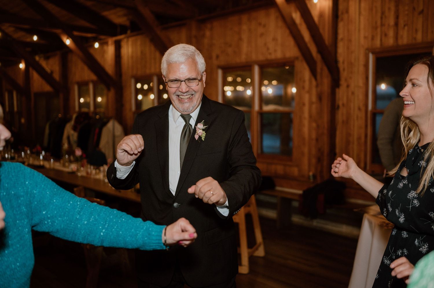 People dancing joyfully at rustic barn wedding reception.