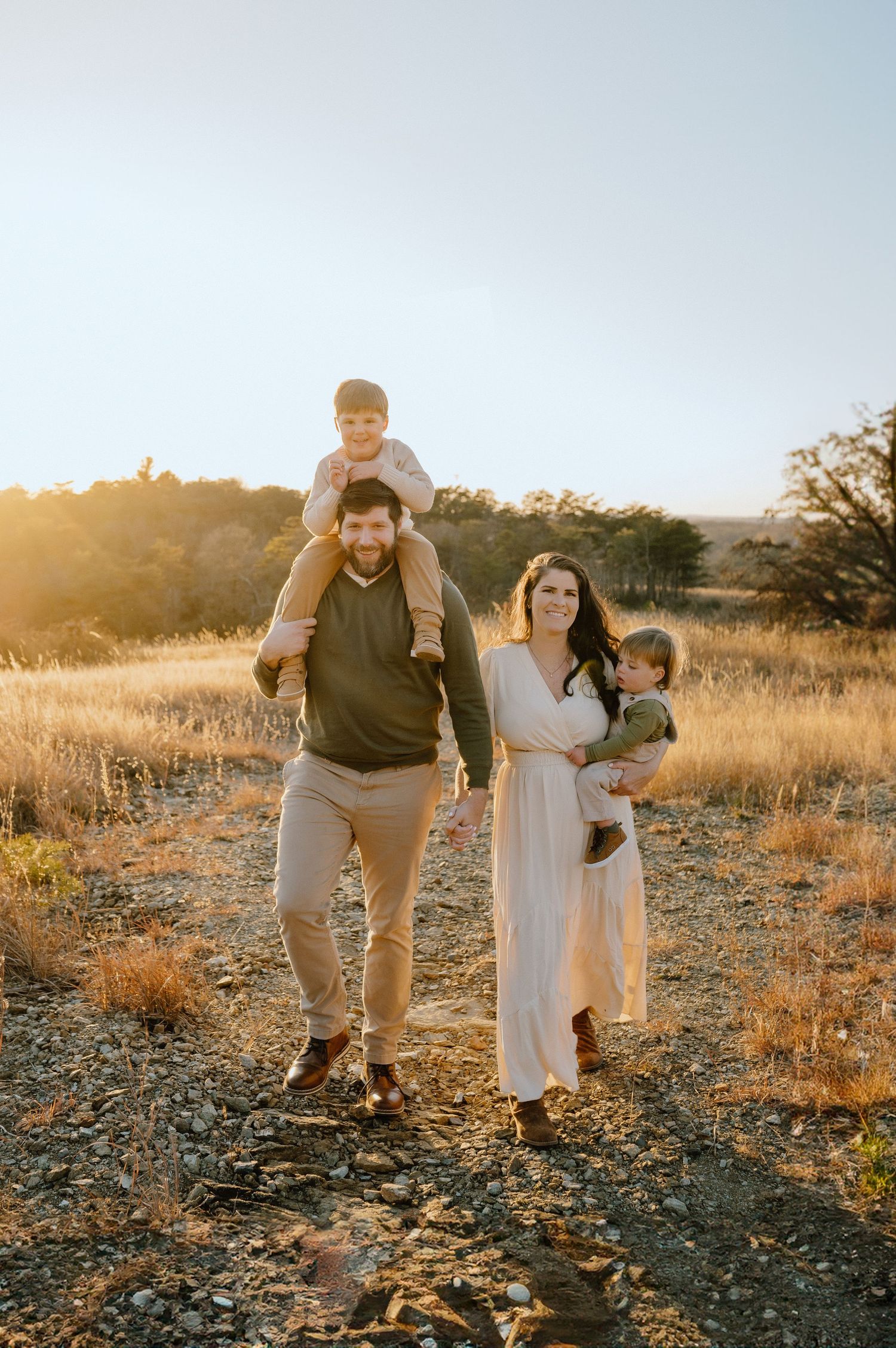 A family enjoys a sunset stroll together through a golden field.