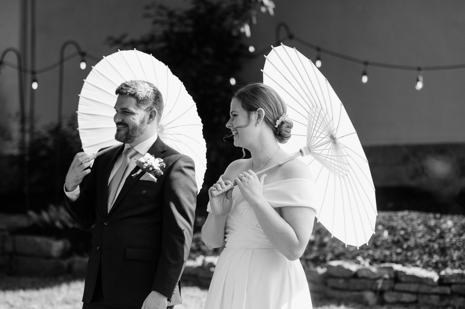 Wedding guests holding decorative white parasols pose together during a celebration.