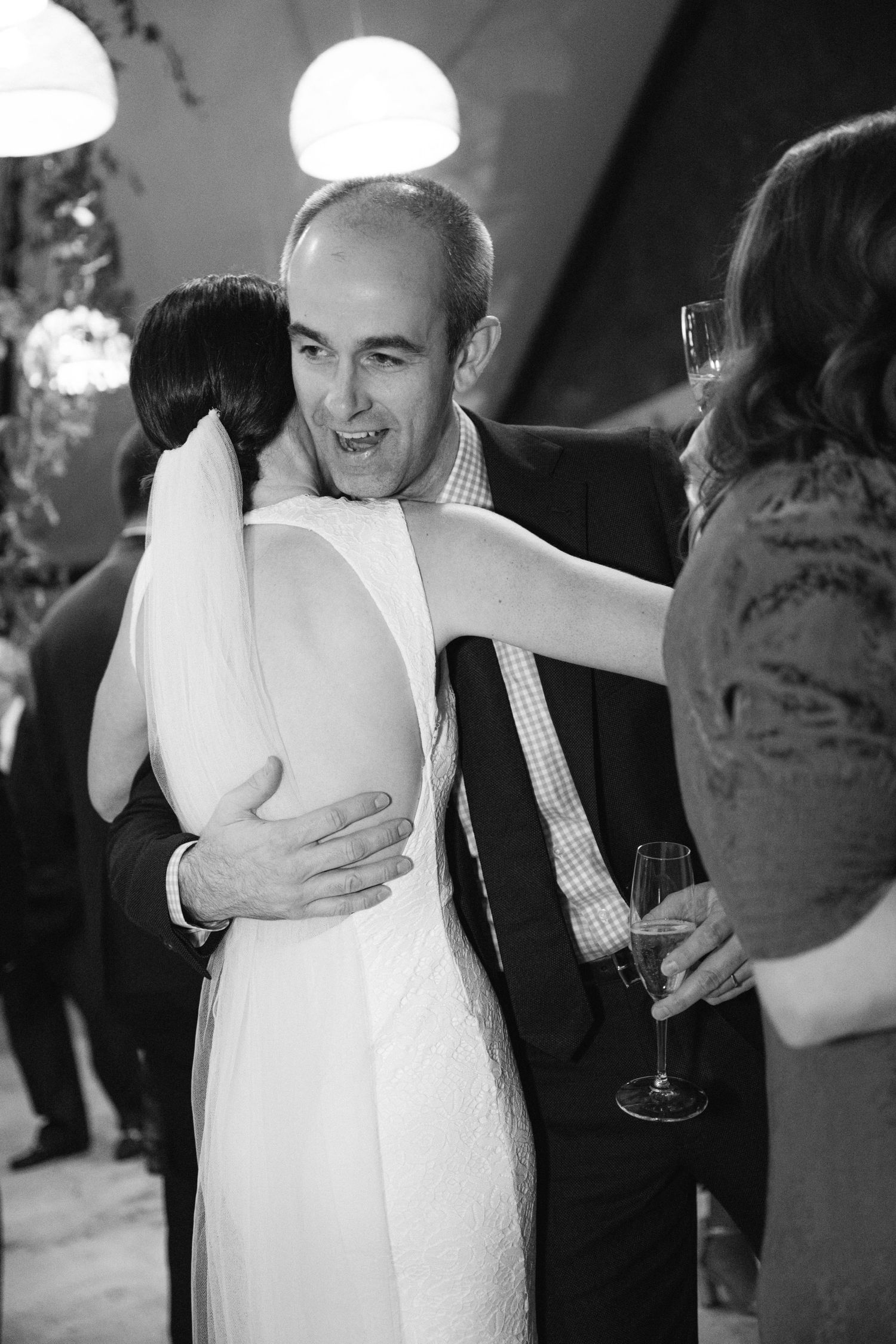 A tender embrace on the dance floor during a wedding reception as a couple shares an intimate moment in black and white.