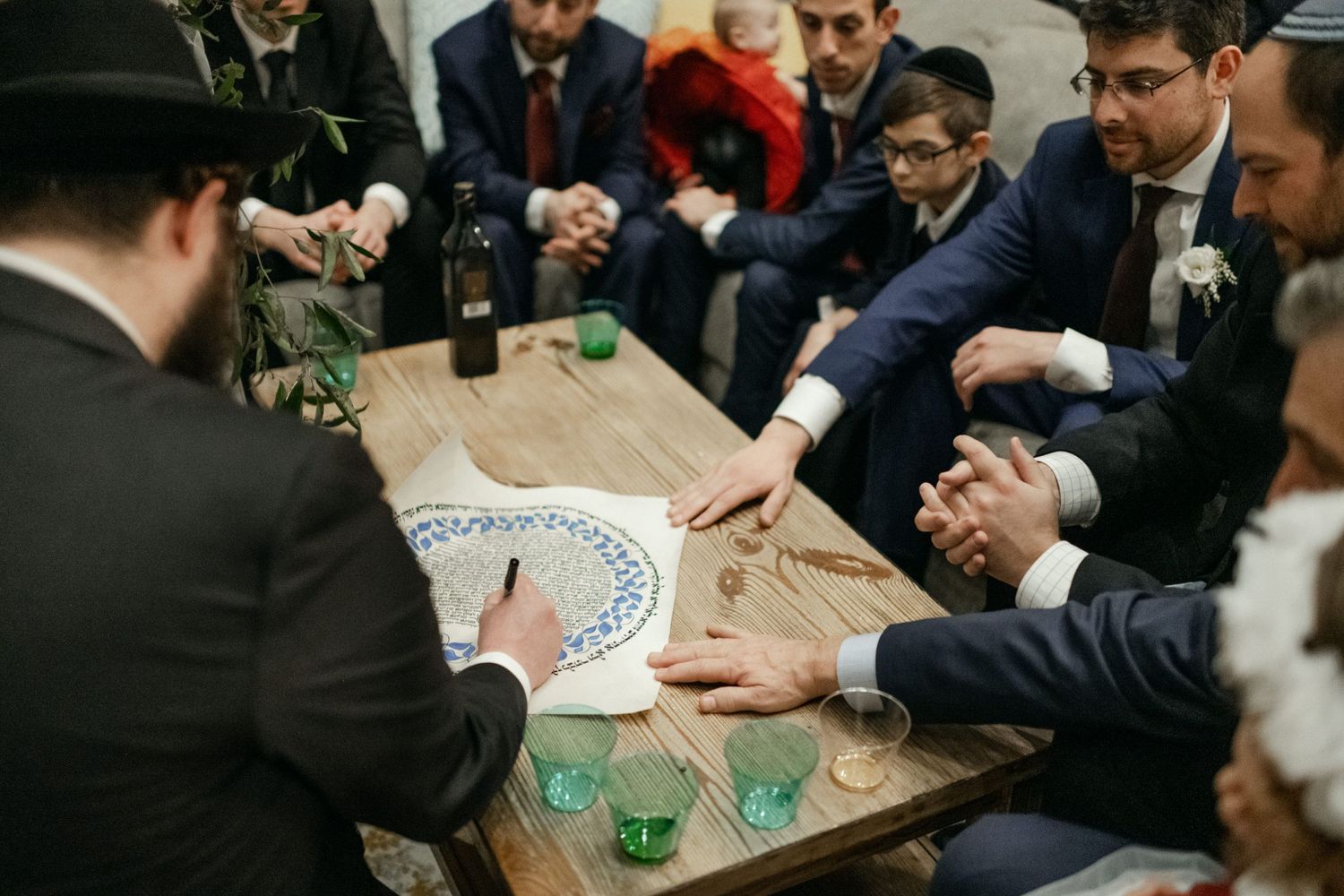 Wedding guests gathered around a wooden table participating in a traditional ceremony.