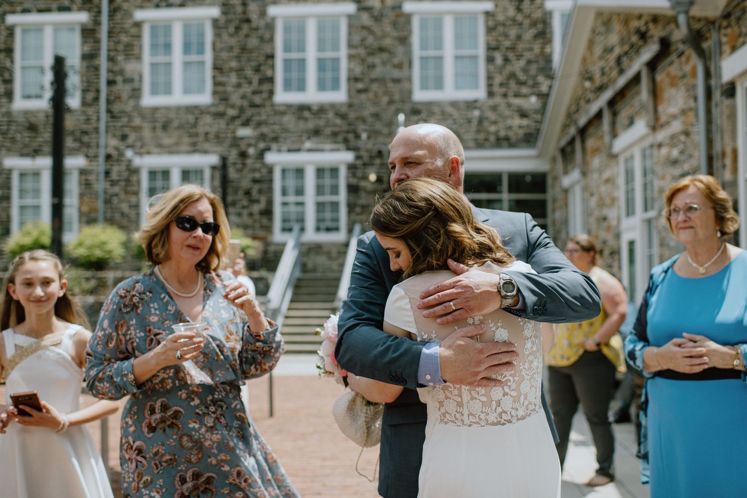 Emotional wedding celebration moment outside historic stone building.