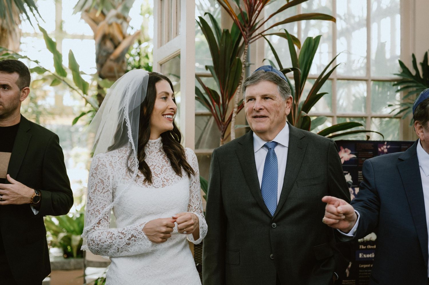 Wedding celebration in a bright greenhouse filled with tropical plants.