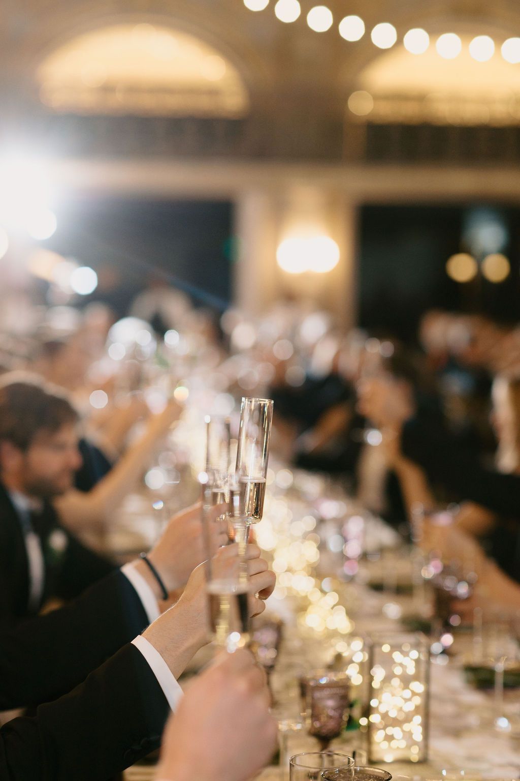 Champagne glasses and twinkling lights create an elegant atmosphere at a formal dinner reception.