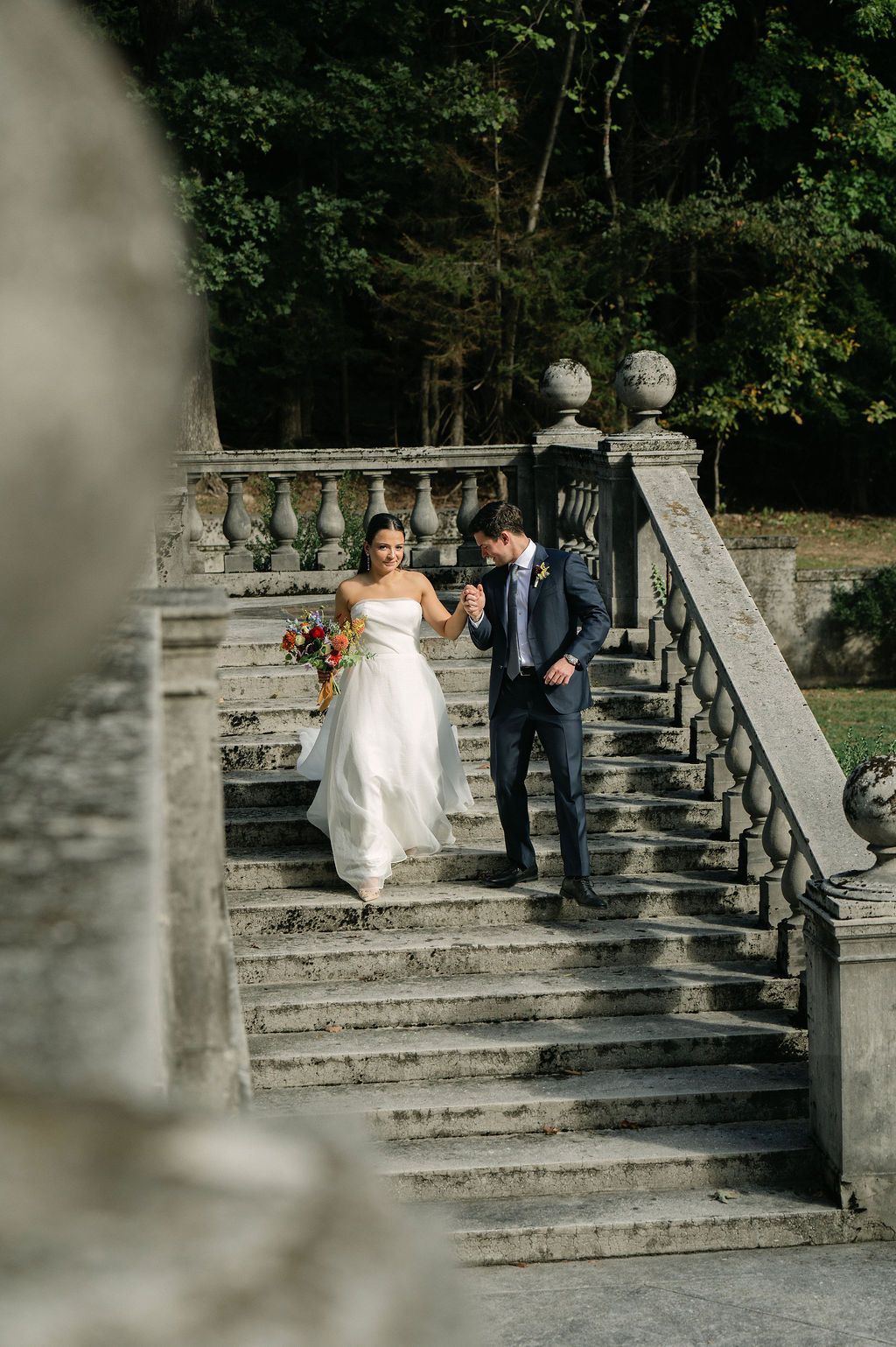 A couple descends stone steps during their wedding photoshoot at a historic venue at Strong Mansion on Sugarloaf Mountain
