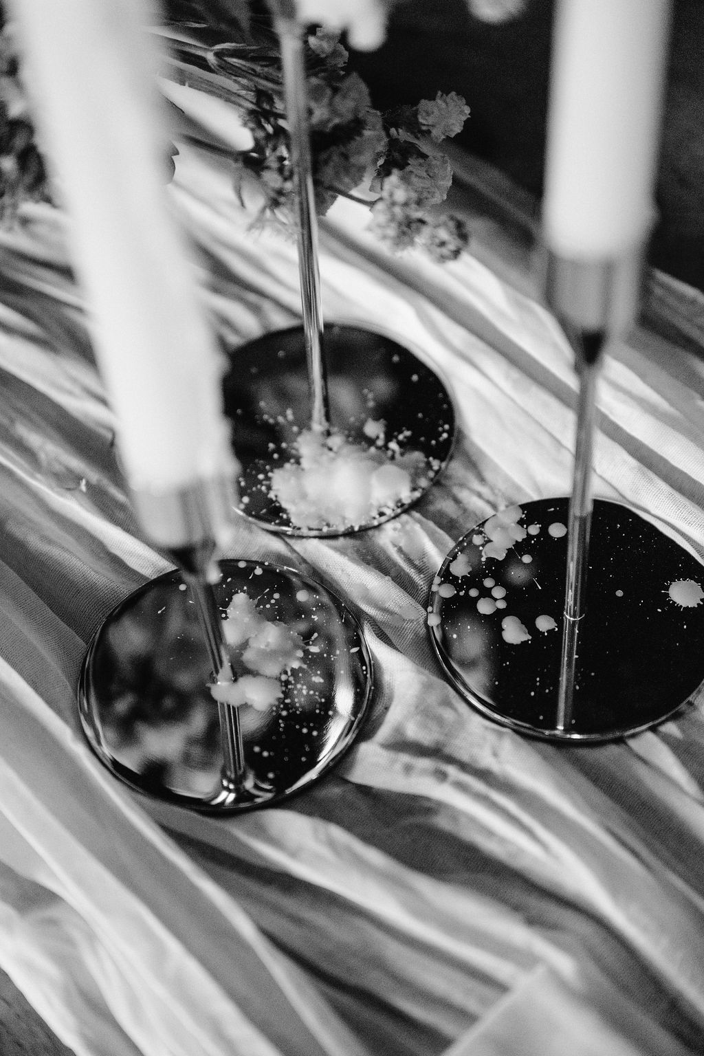 Black and white close-up of decorative candle holders on a textured tablecloth Fadensonnon in Baltimore