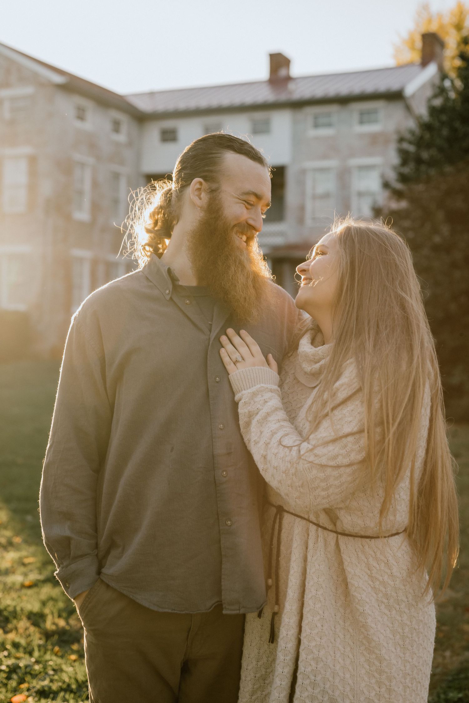 A couple shares a romantic moment in warm sunset light outside a historic building.