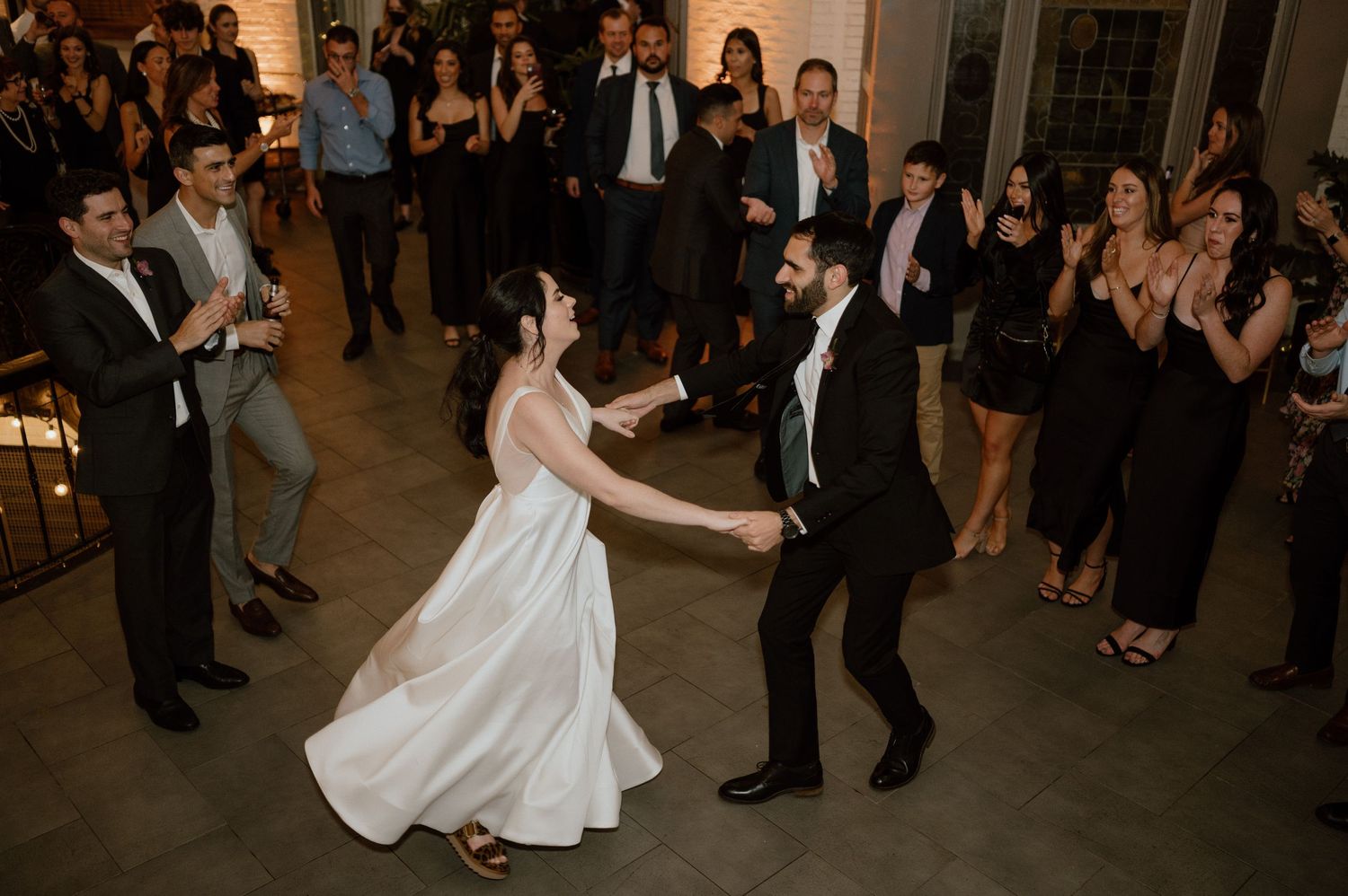 Wedding couple performs first dance while guests watch and celebrate.