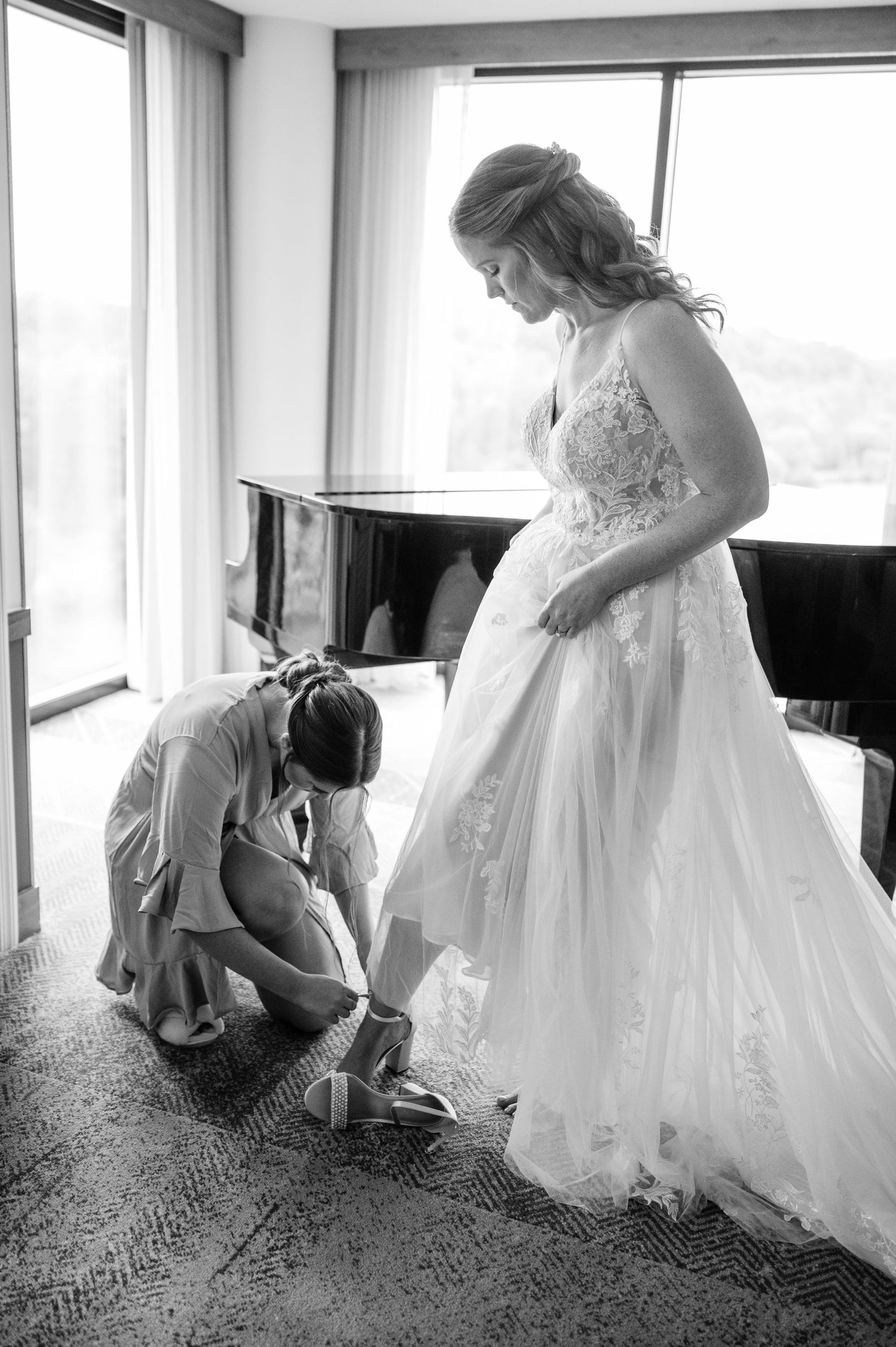 Black and white photo of final wedding dress preparations as shoes are put on before the ceremony.