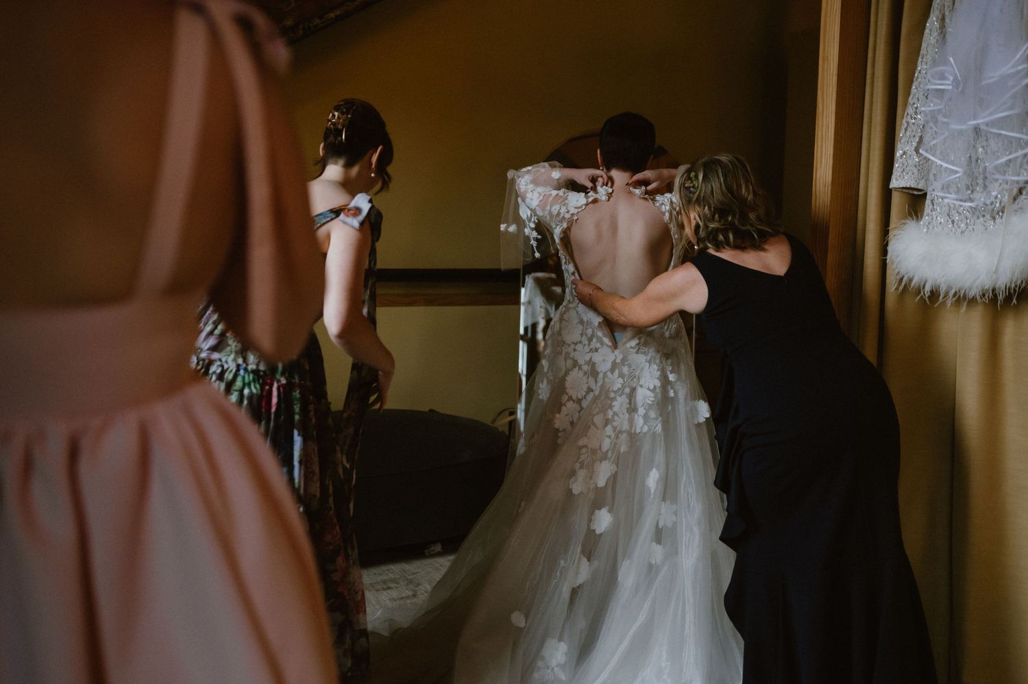 Behind-the-scenes moment of wedding dress preparation in a dimly lit room.