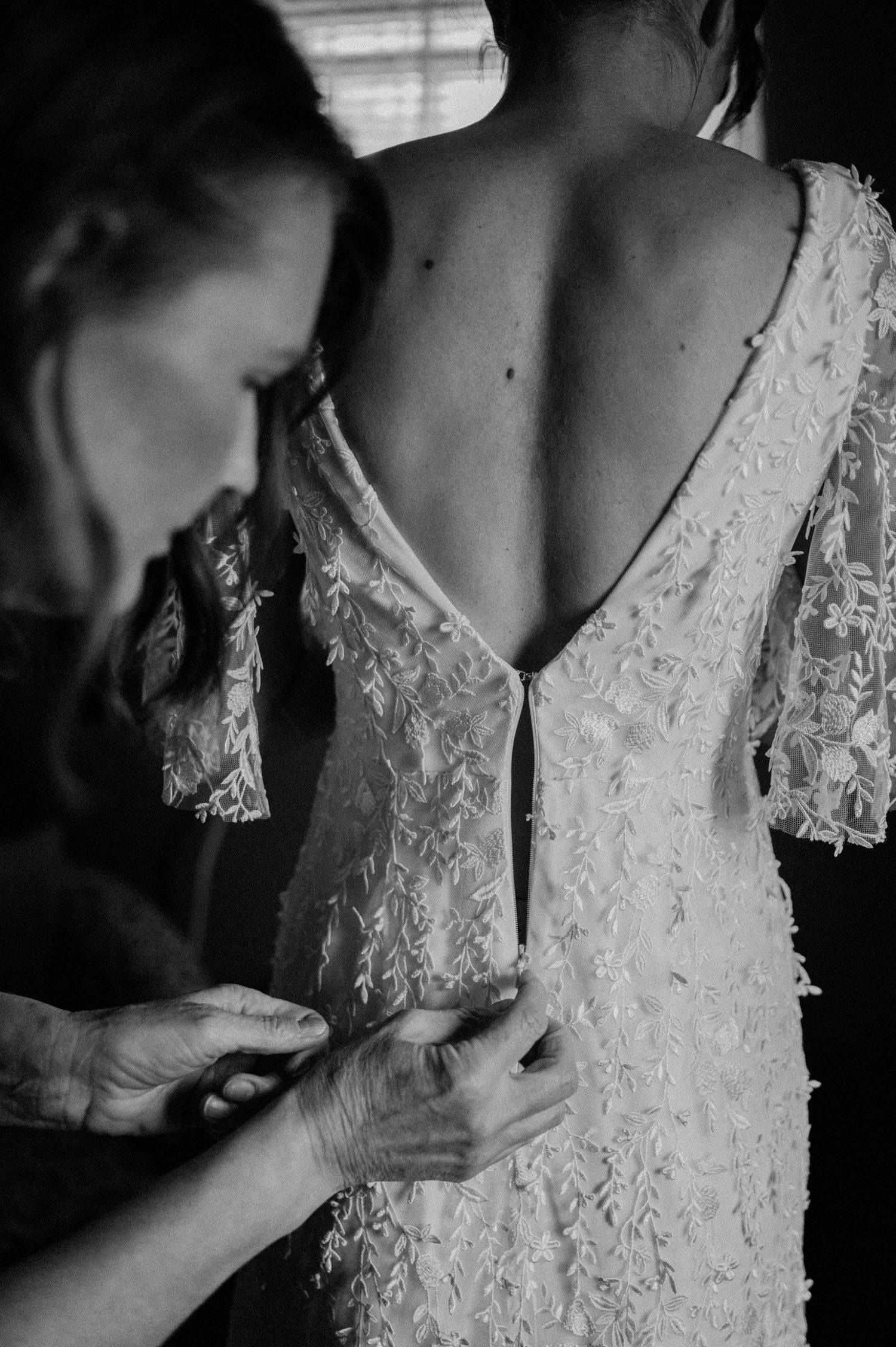 Close-up black and white image of intricate lace details and buttons on a wedding dress back.