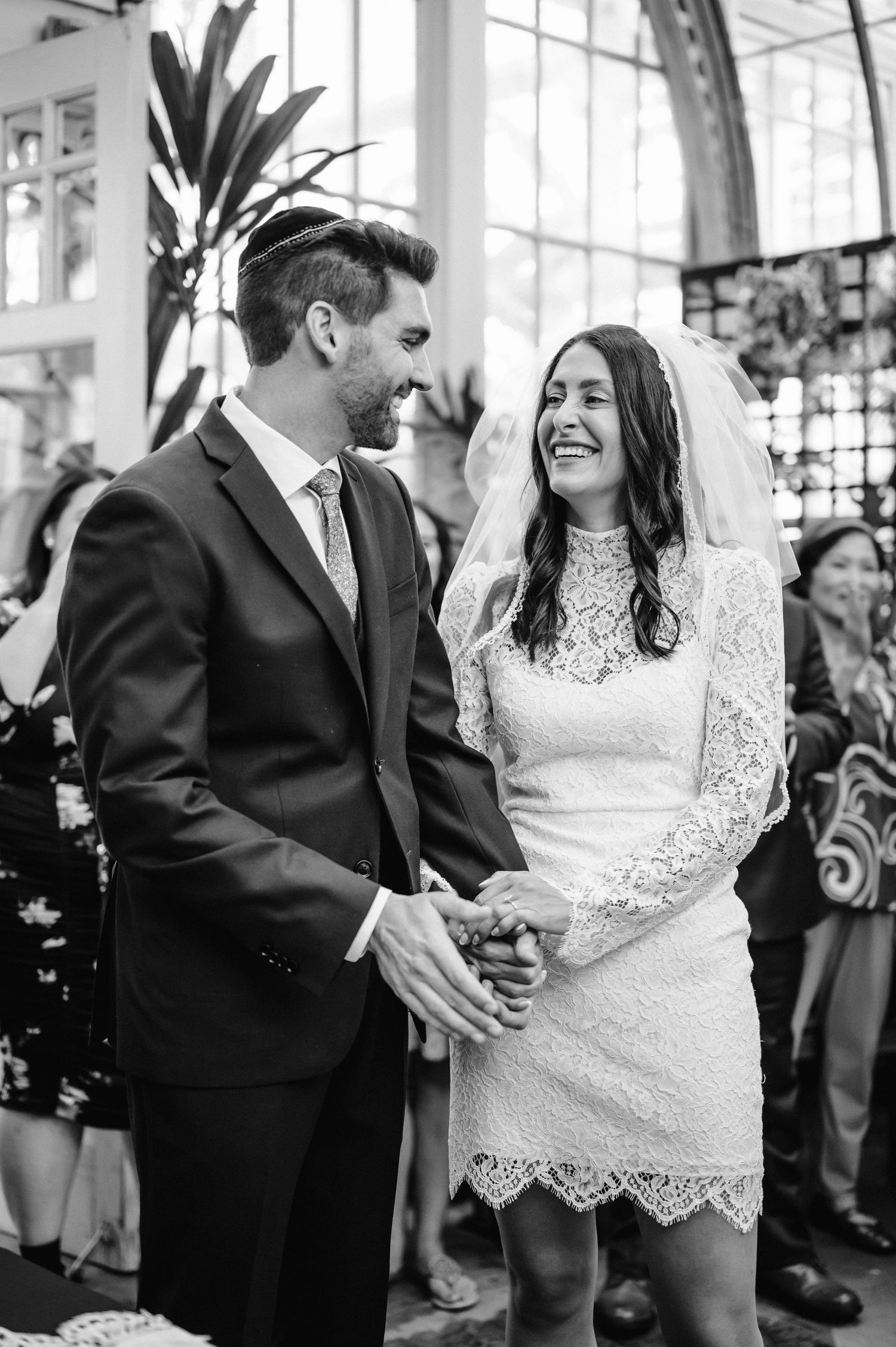 Black and white portrait of newlyweds sharing intimate moment in greenhouse.