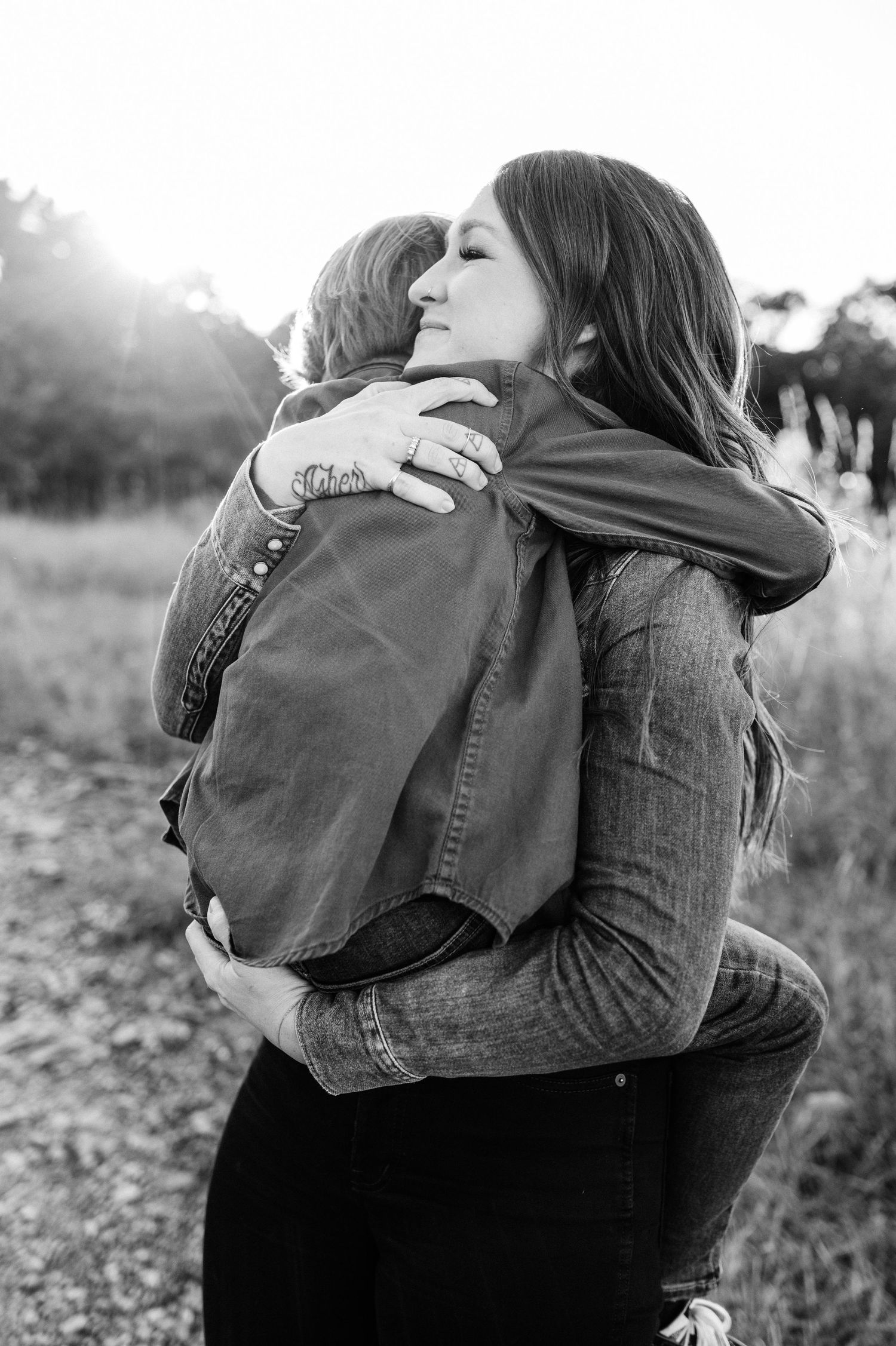Black and white image of tender embrace in sunlit field.