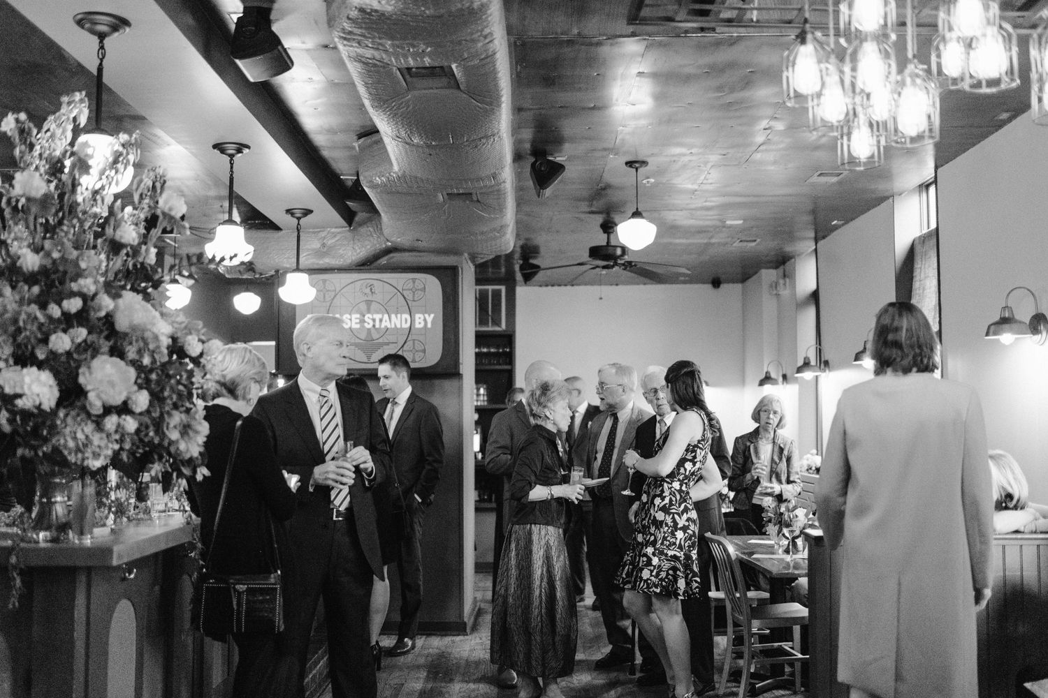 Black and white photo of wedding guests mingling at an elegant reception venue.