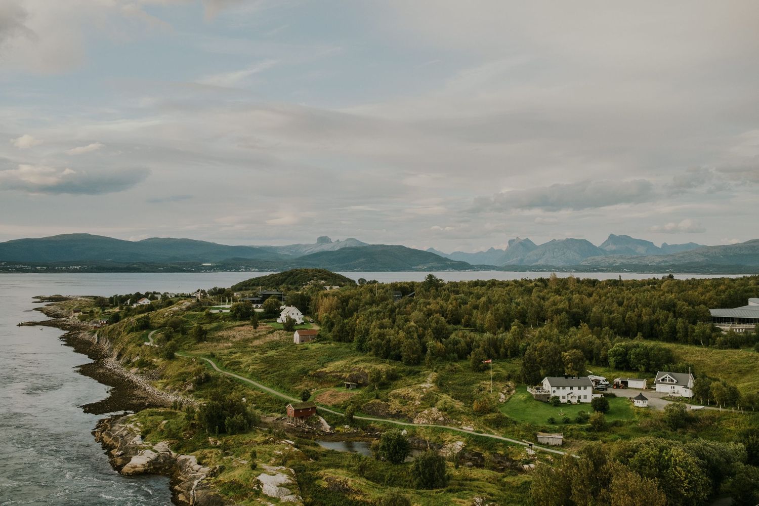 Coastal landscape view with mountains and scattered settlements along Norwegian shoreline.