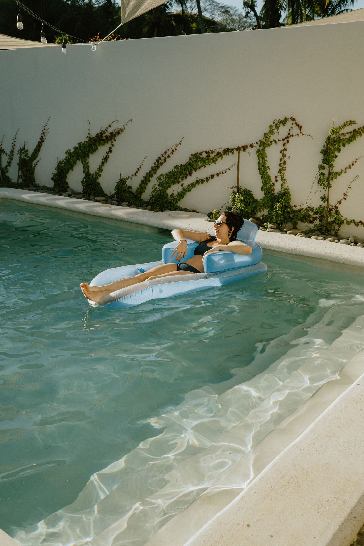 Two people relaxing on a blue pool float in a private swimming pool.