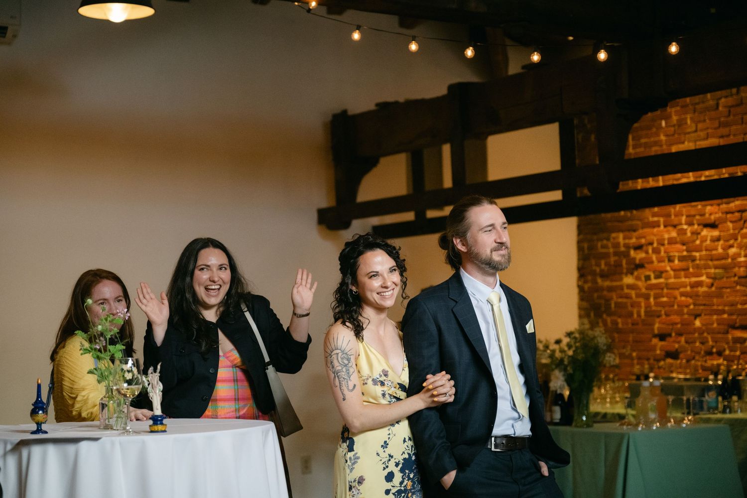 People celebrating at an indoor event with exposed brick walls and warm lighting.