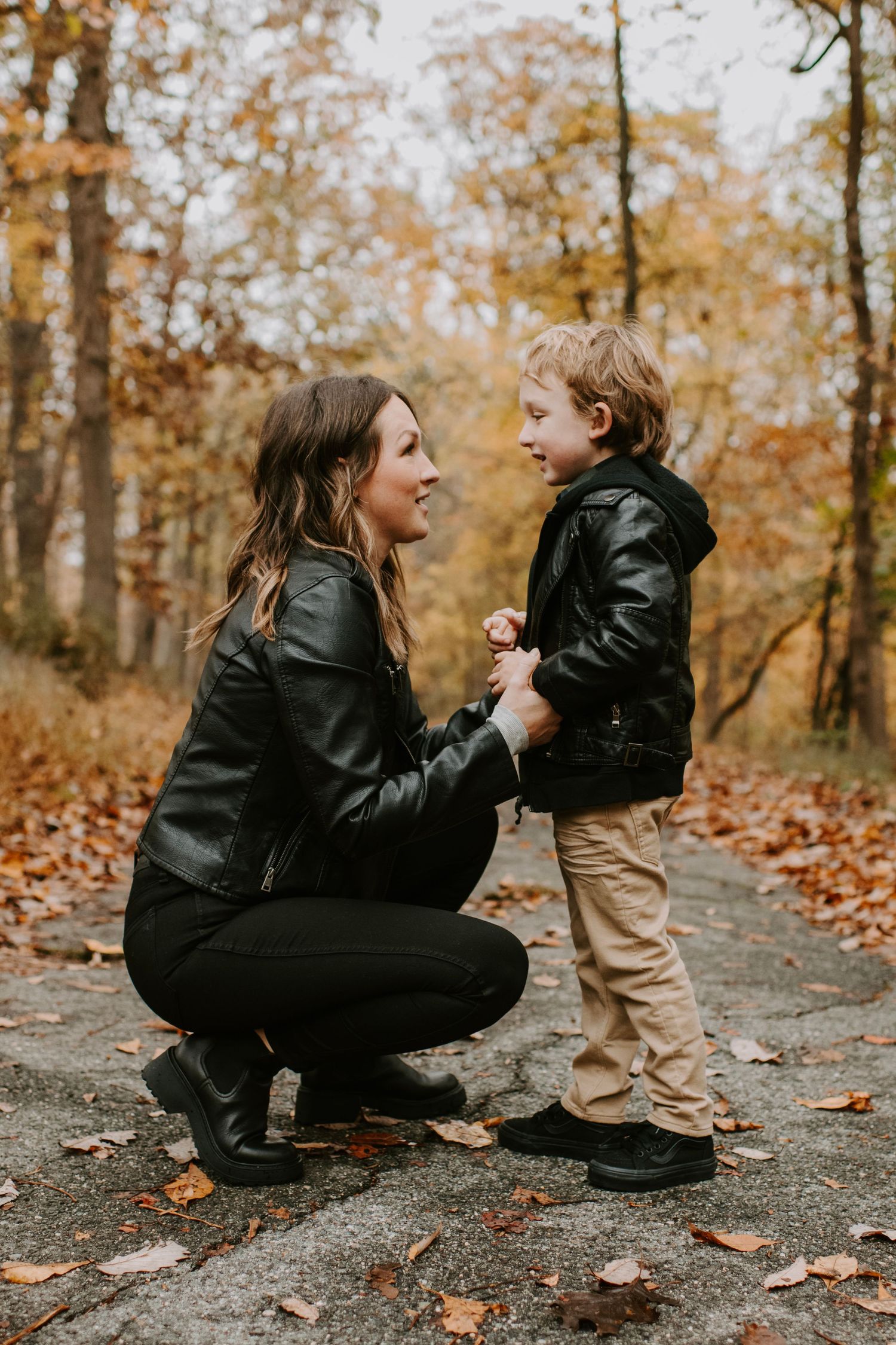 Tender moment shared on a leaf-covered forest path during autumn.