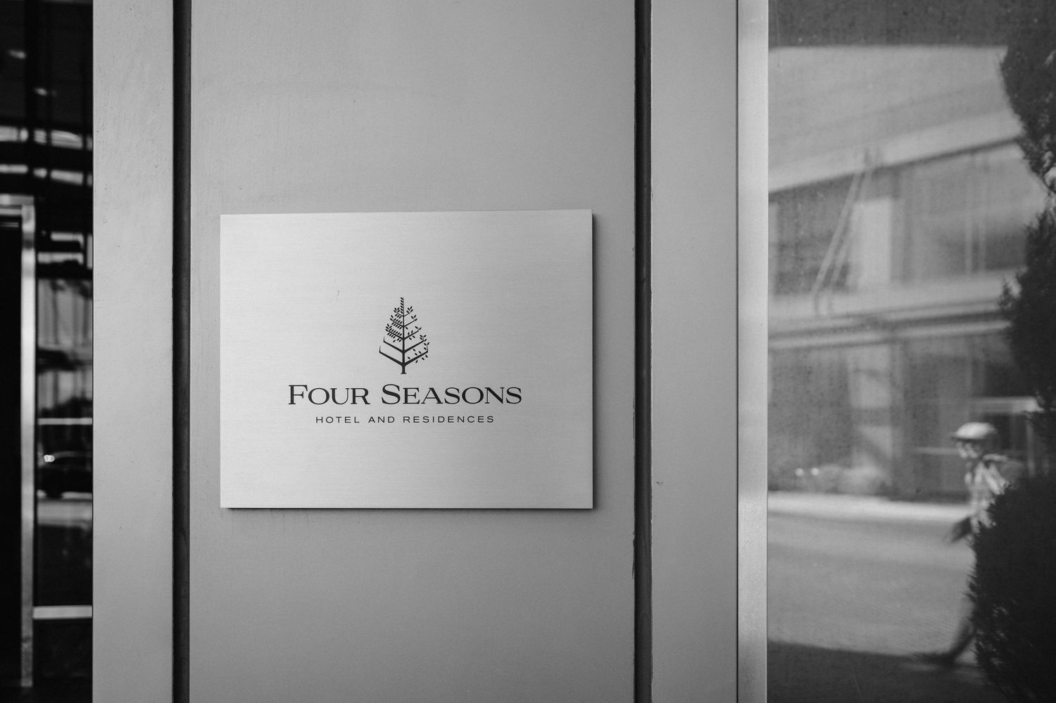 Four Seasons hotel logo displayed on a gray wall in black and white.