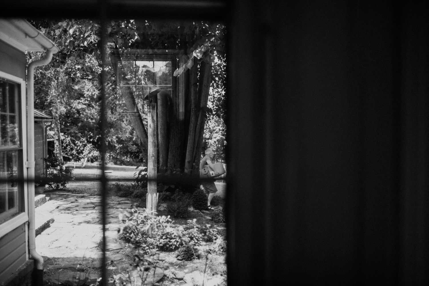 Sunlit garden view through an open doorway in black and white.