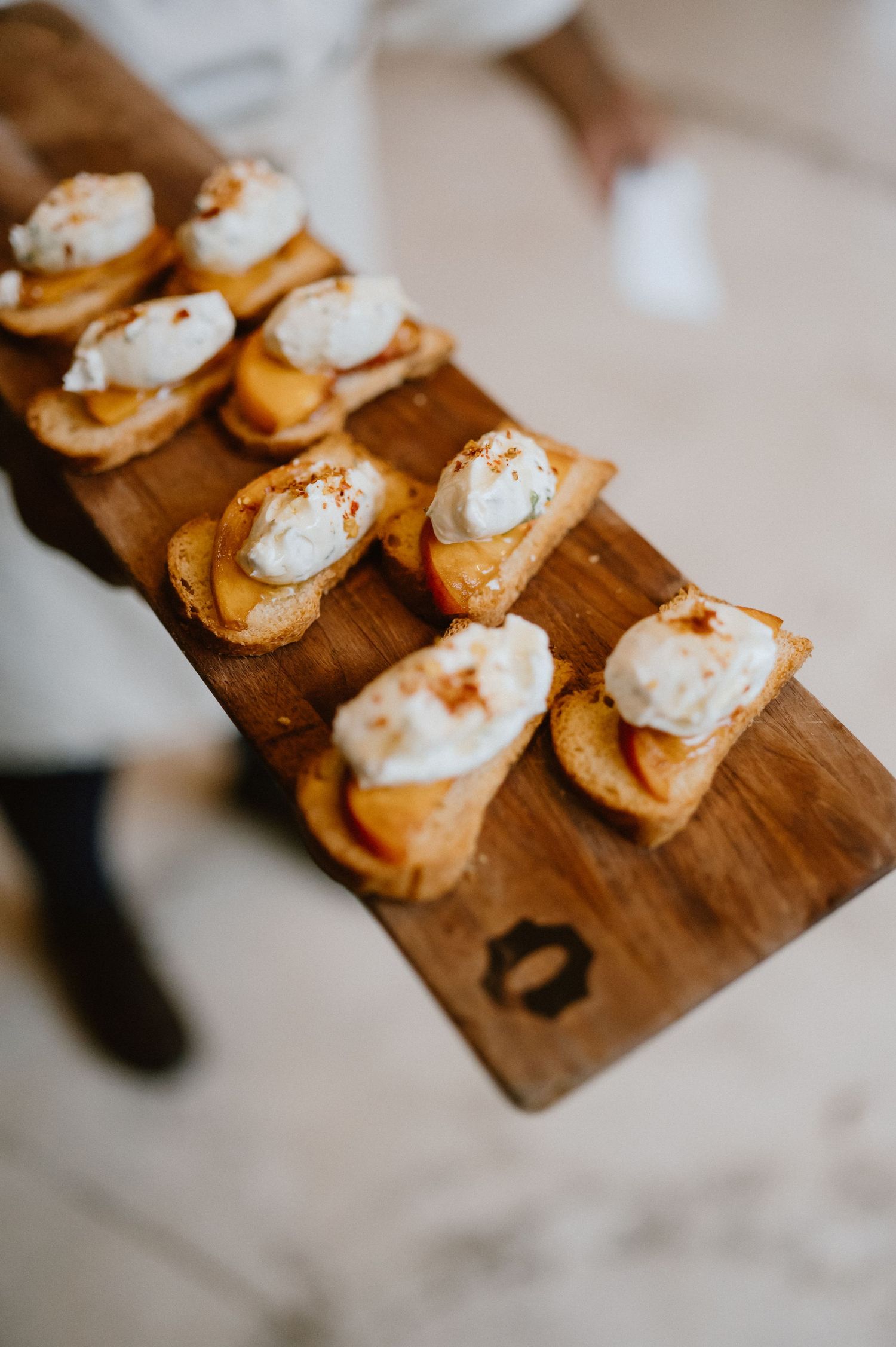 Small appetizers with whipped topping served on a rustic wooden board.
