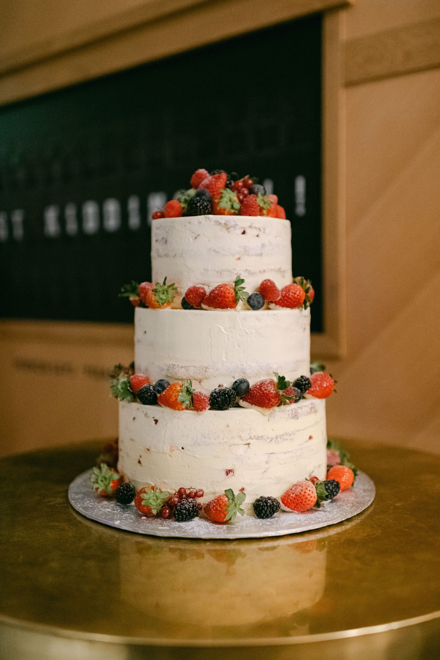 Three-tiered white wedding cake decorated with fresh strawberries, blueberries and raspberries.