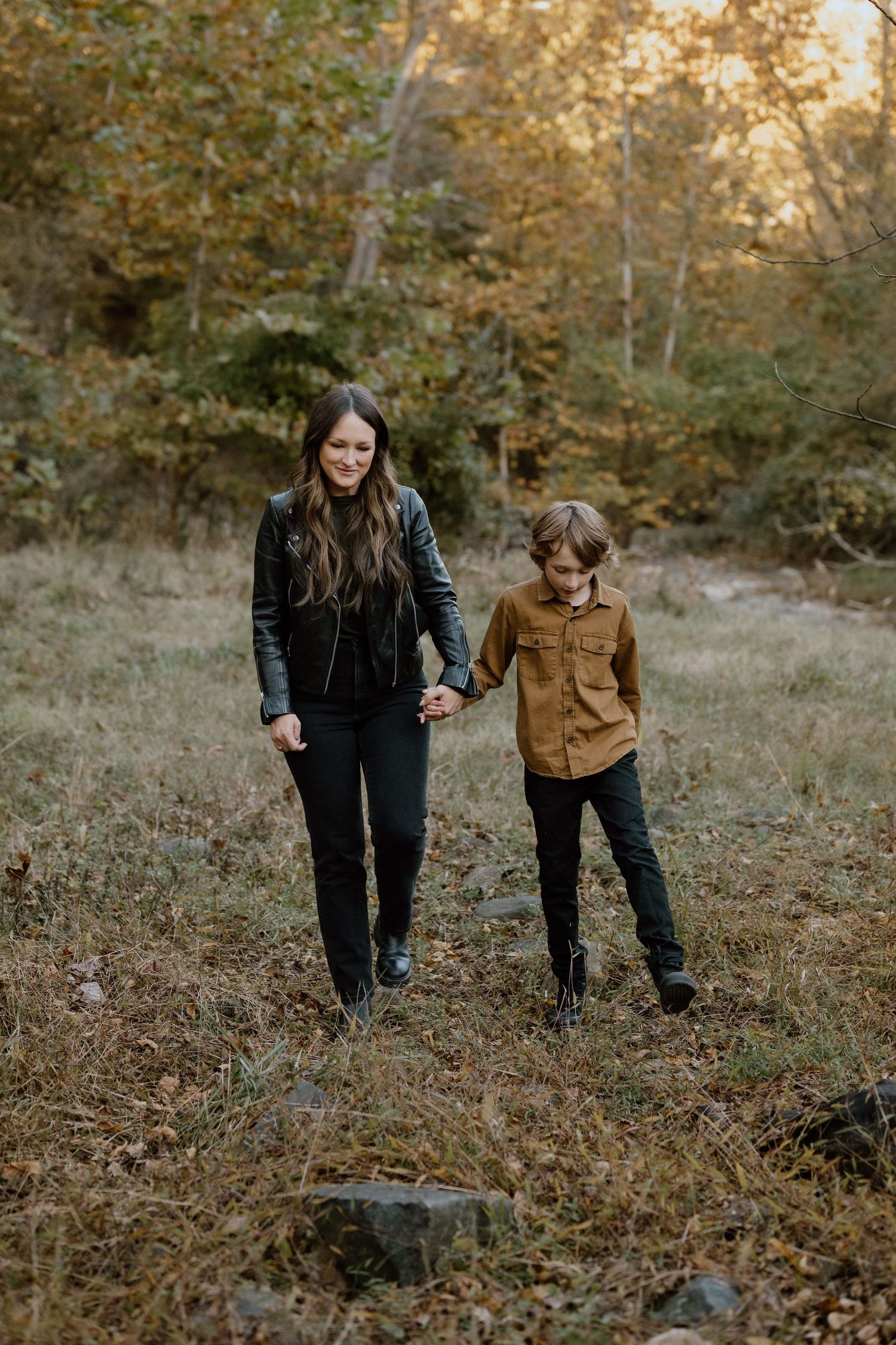 Two people walk together through a golden autumn forest setting.