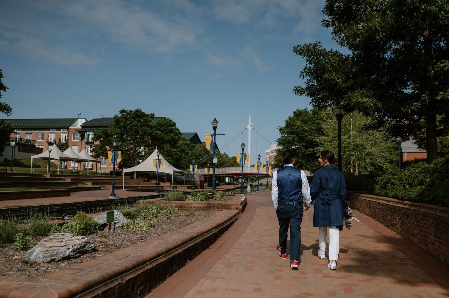 Two people walking on a brick path with church spires visible in the background.