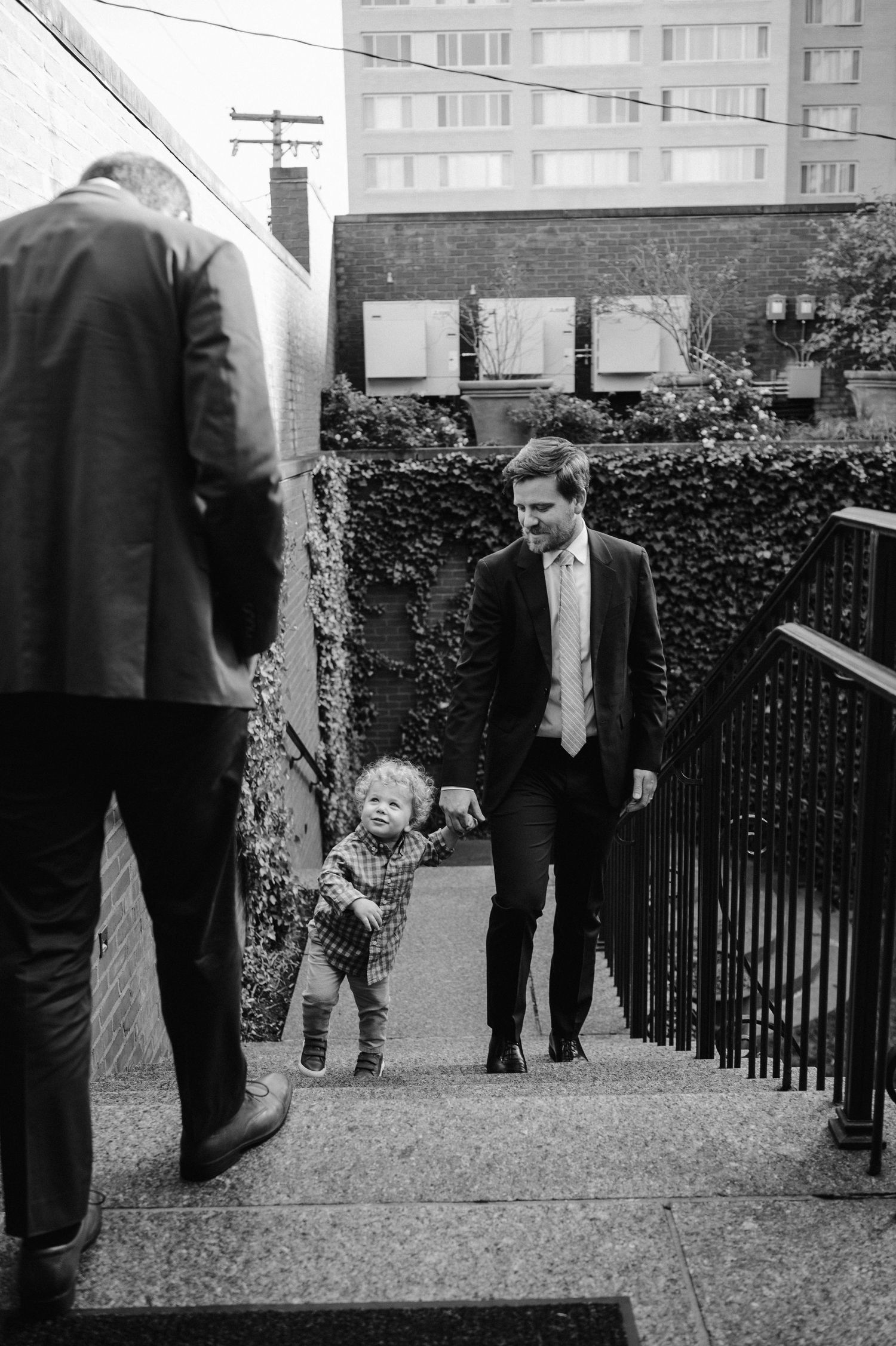 Black and white image of people and a small child ascending outdoor stairs.