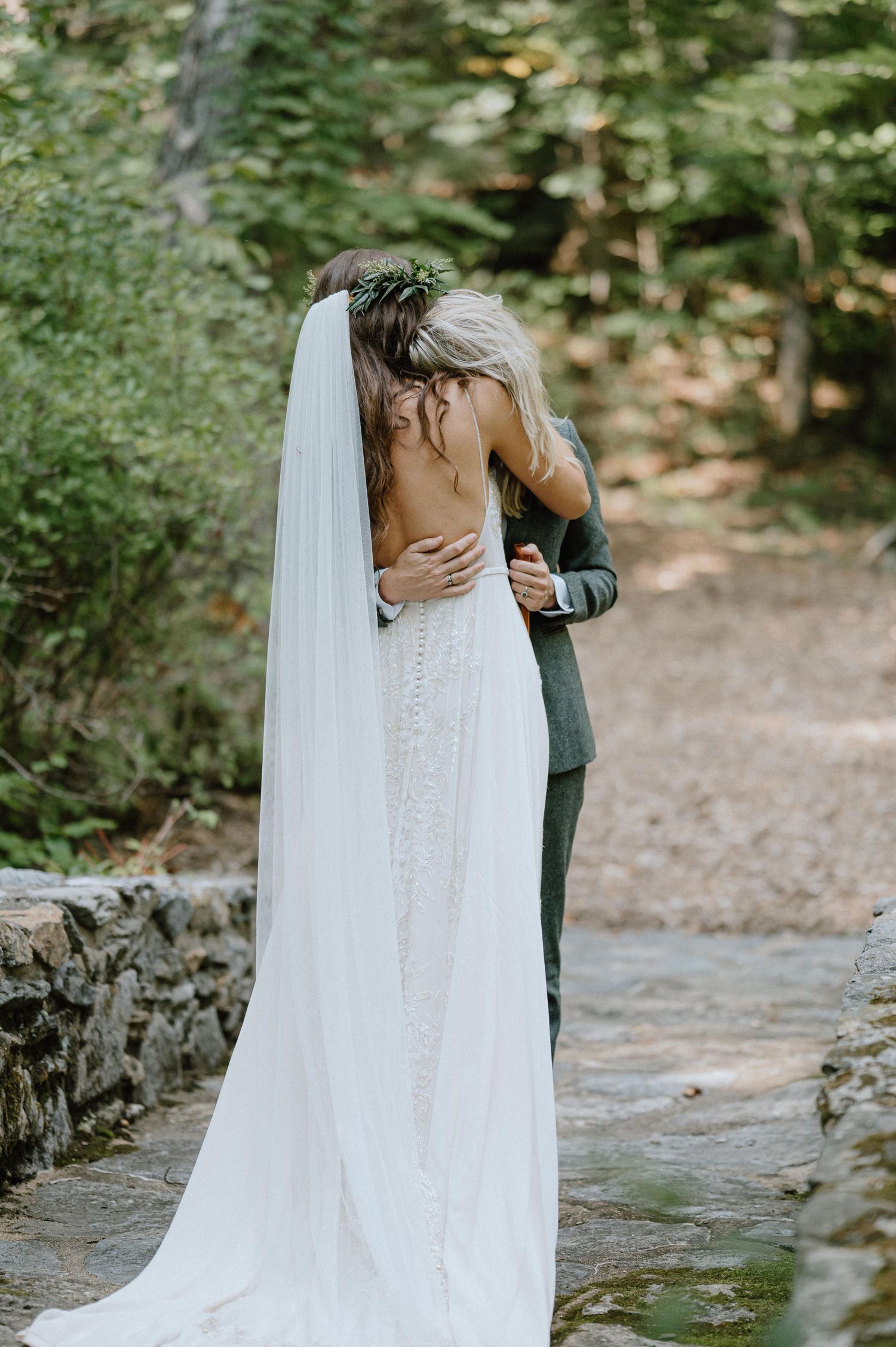 A romantic embrace captured between newlyweds on a stone-lined forest path.