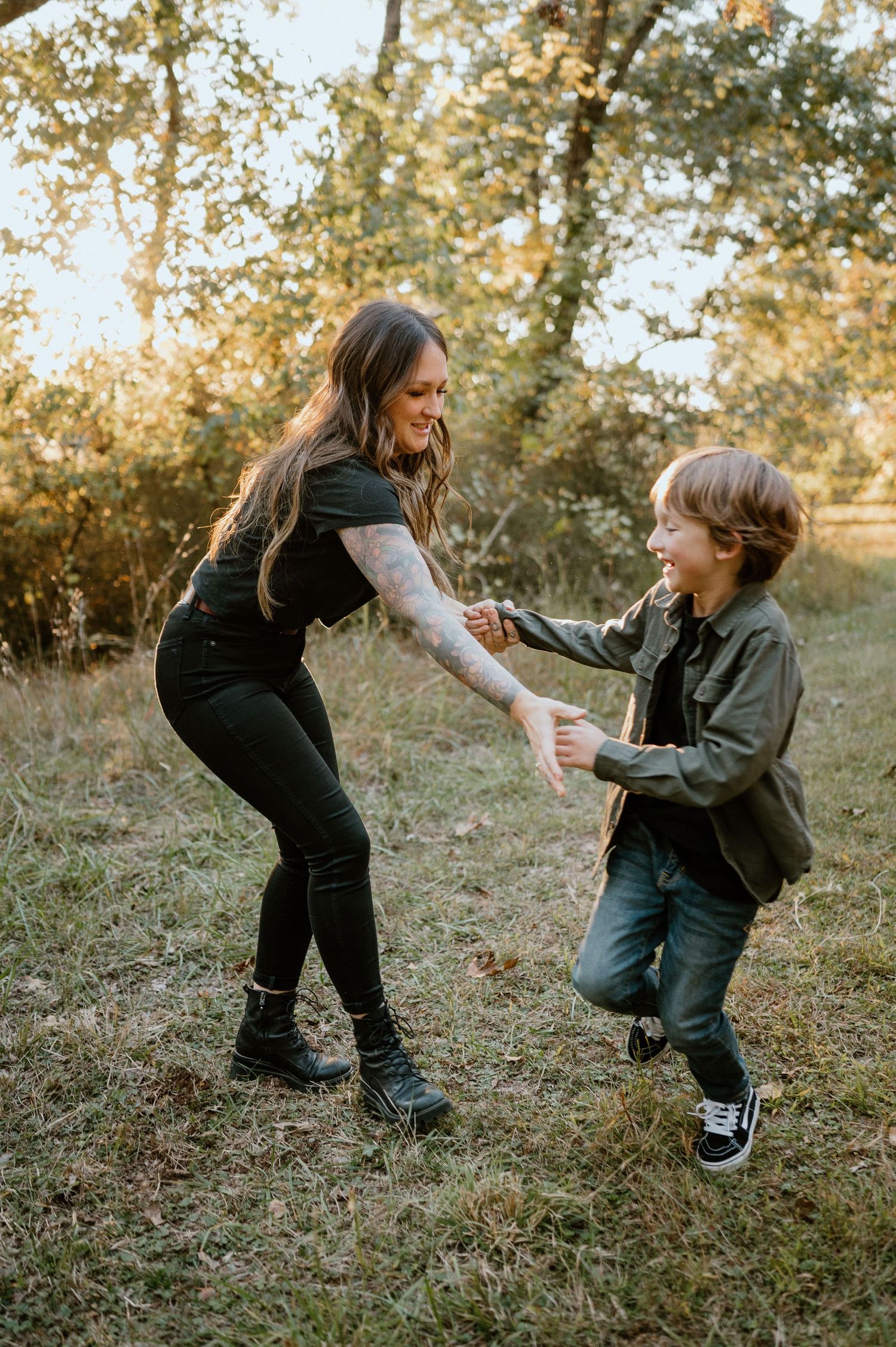 A playful outdoor moment captured in warm autumn sunlight with someone dancing and playing with a child.