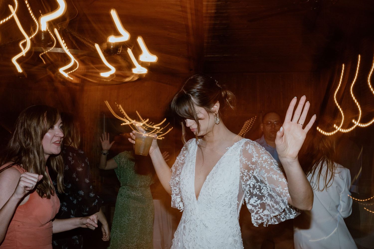 People dancing under twinkle lights at wedding reception party.