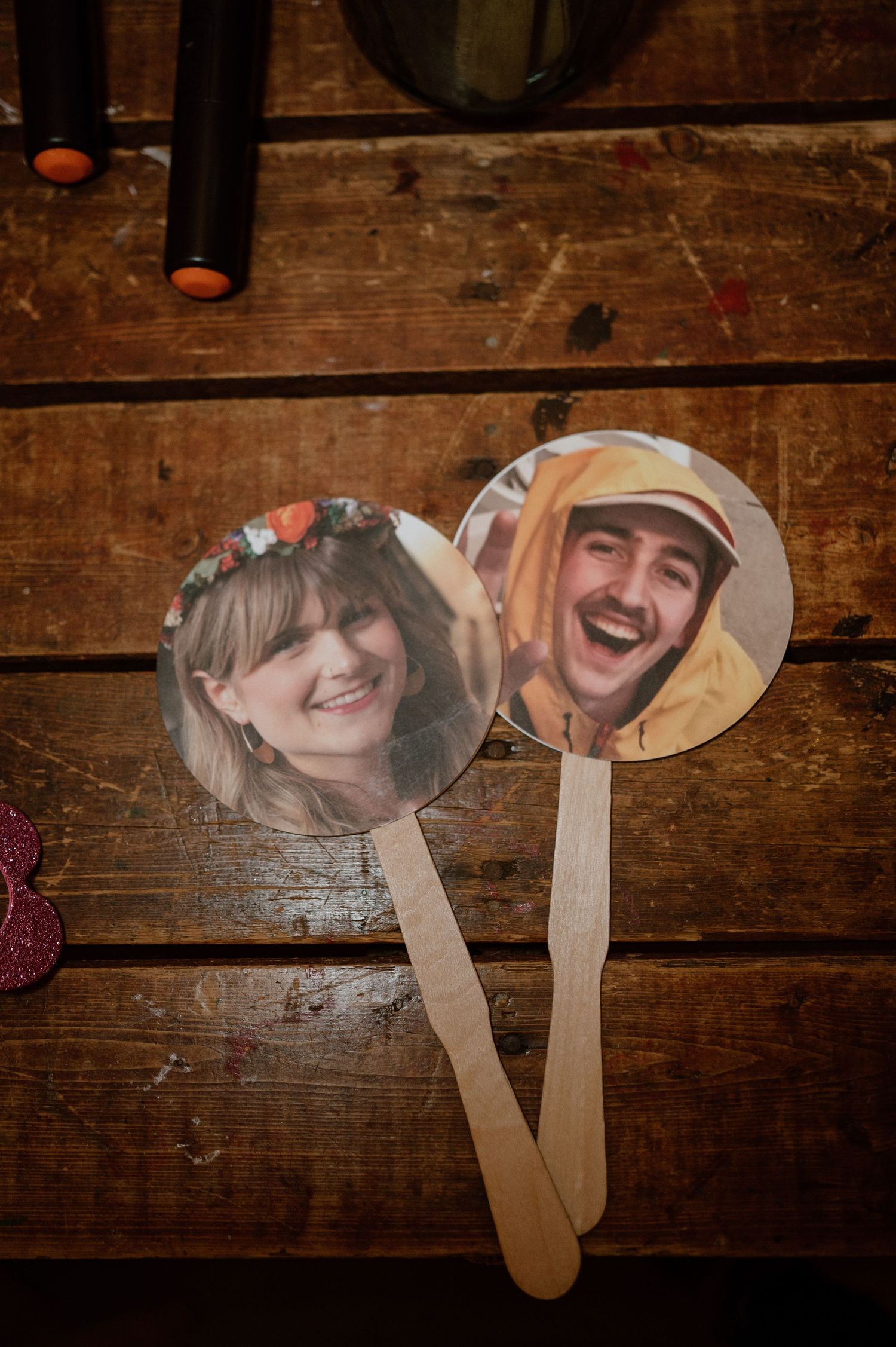 Two decorative photo fans displayed on rustic wooden surface showing wedding couple portraits.