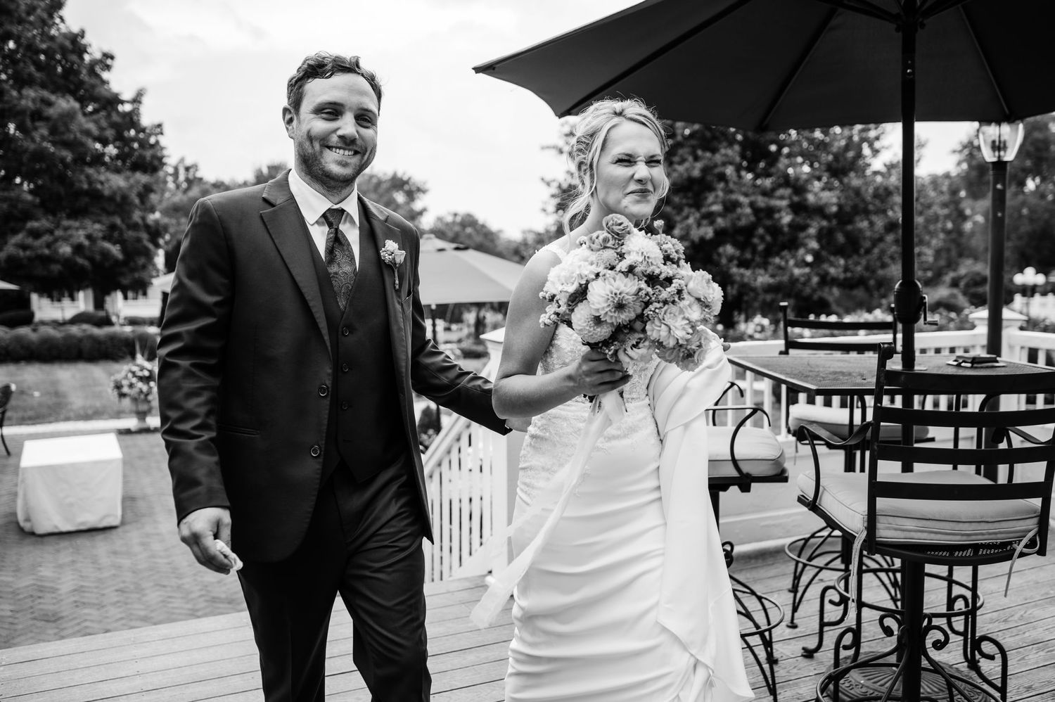 A couple shares a joyful moment on their wedding day on an outdoor patio.