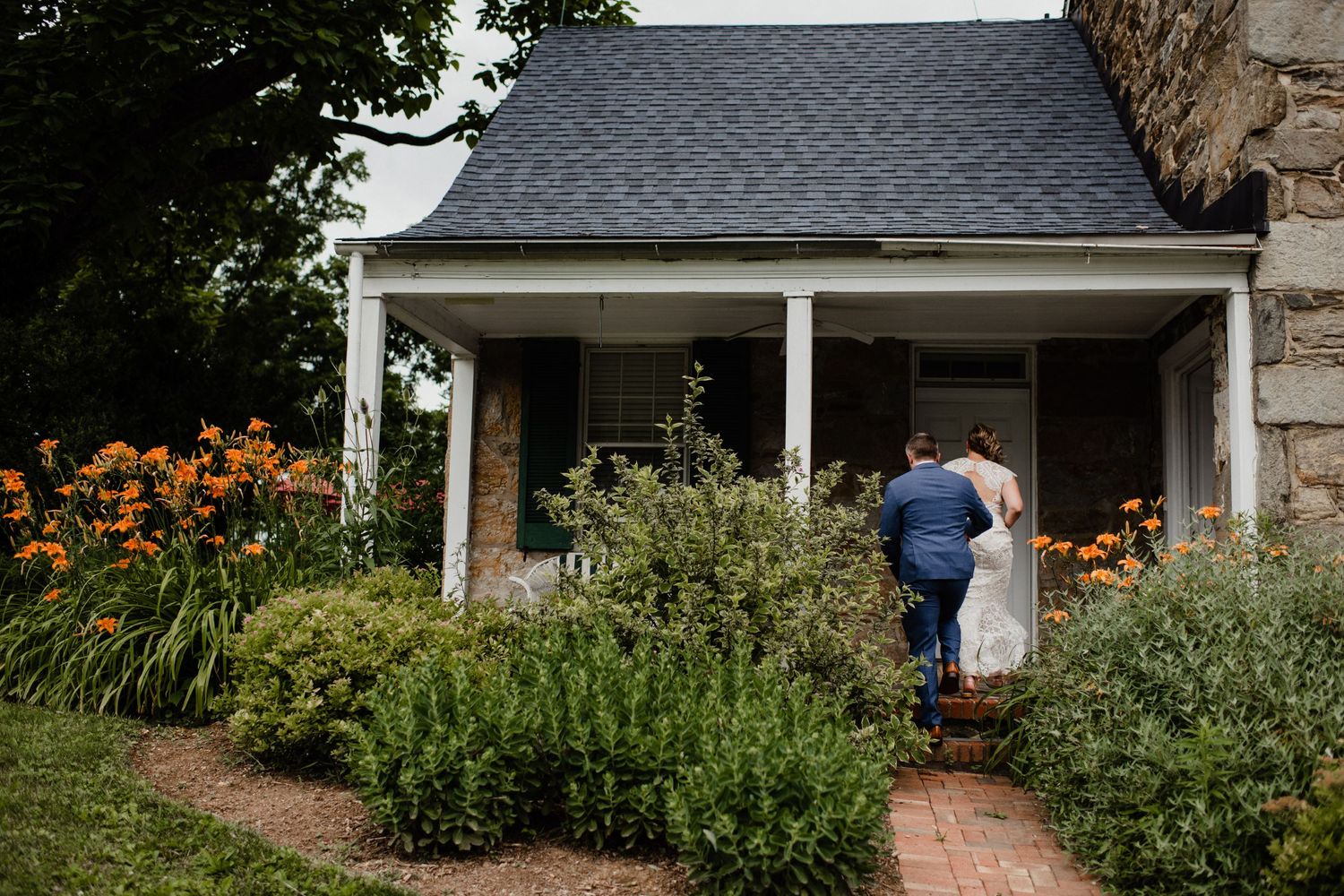 A romantic garden scene with orange flowers and a charming covered porch entrance.
